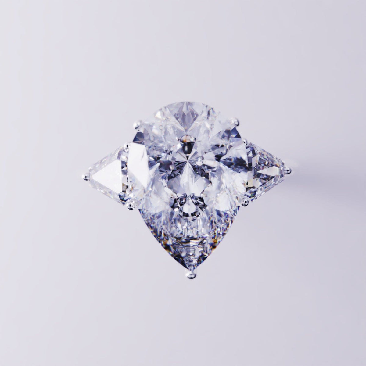 Silver-toned ring with a large pear-cut clear center stone flanked by two triangular side stones.