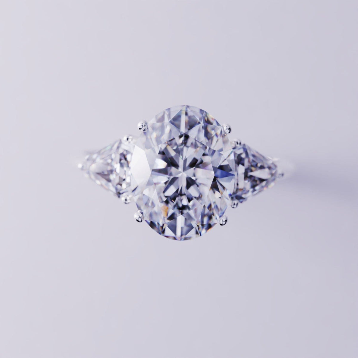 Three-stone ring with a large oval-cut center stone and triangular side stones on a silver-toned band.