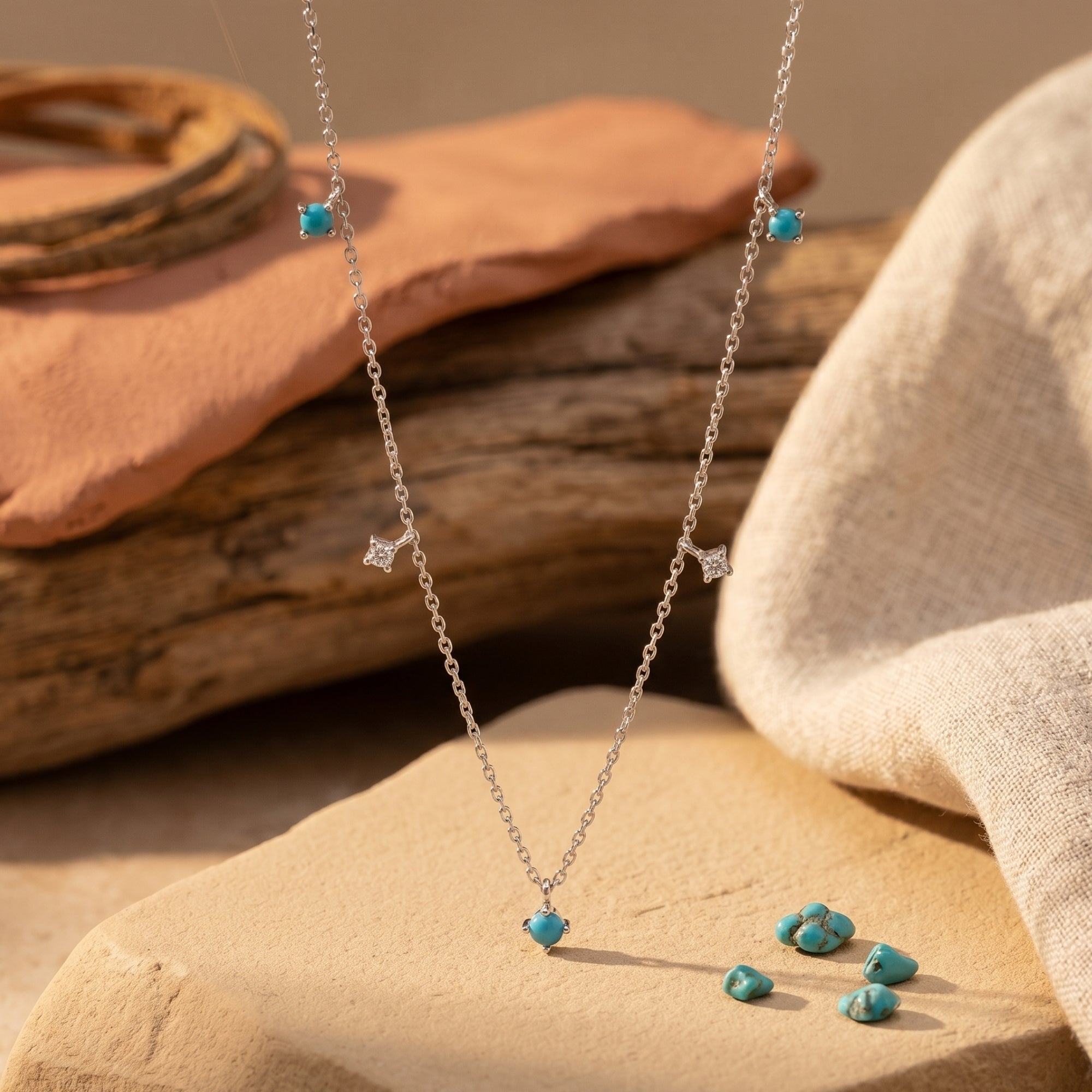Silver turquoise necklace with star accents draped over desert stones in a Southwestern lifestyle setting.