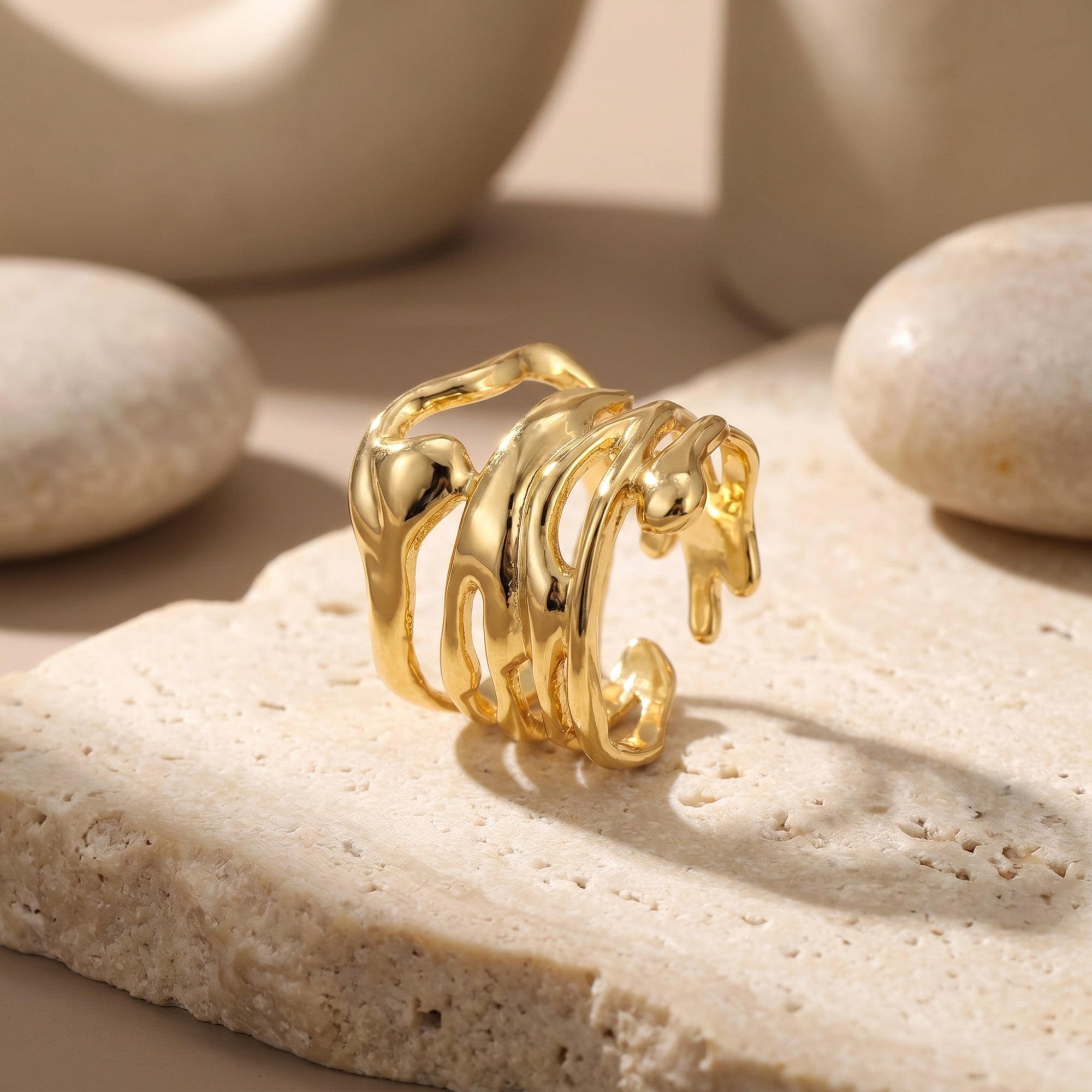 Gold plated Marinella ring with fluid silhouette on textured stone.