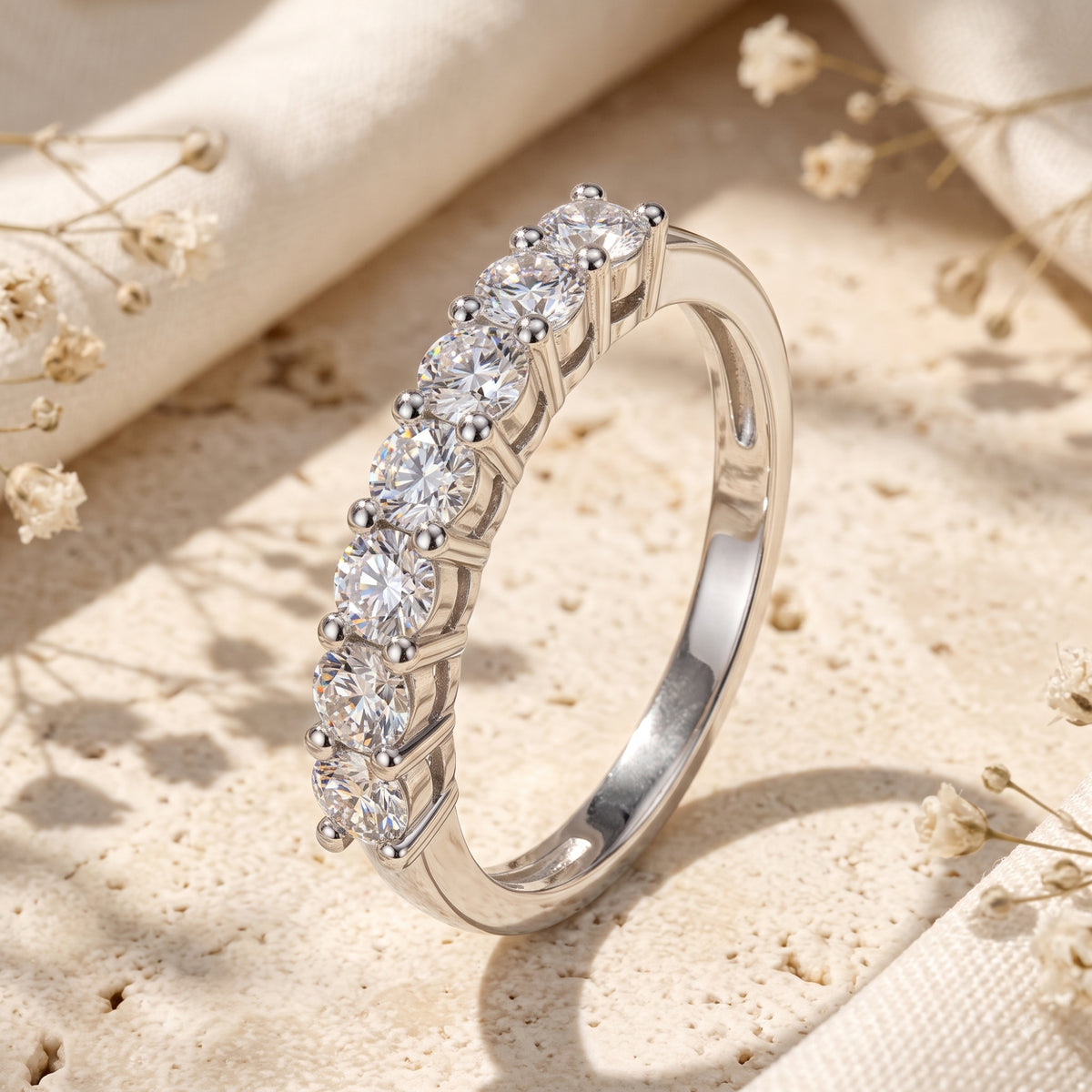 Close-up macro view of a silver band ring with seven round clear stones set in shared prongs.