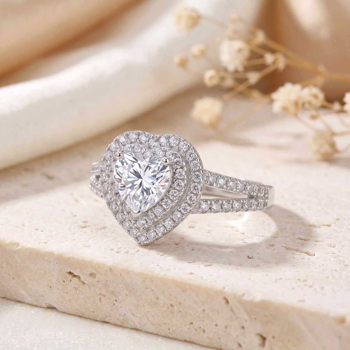 Close-up of a silver heart-shaped ring with two halos of clear accent stones and a split-shank band.