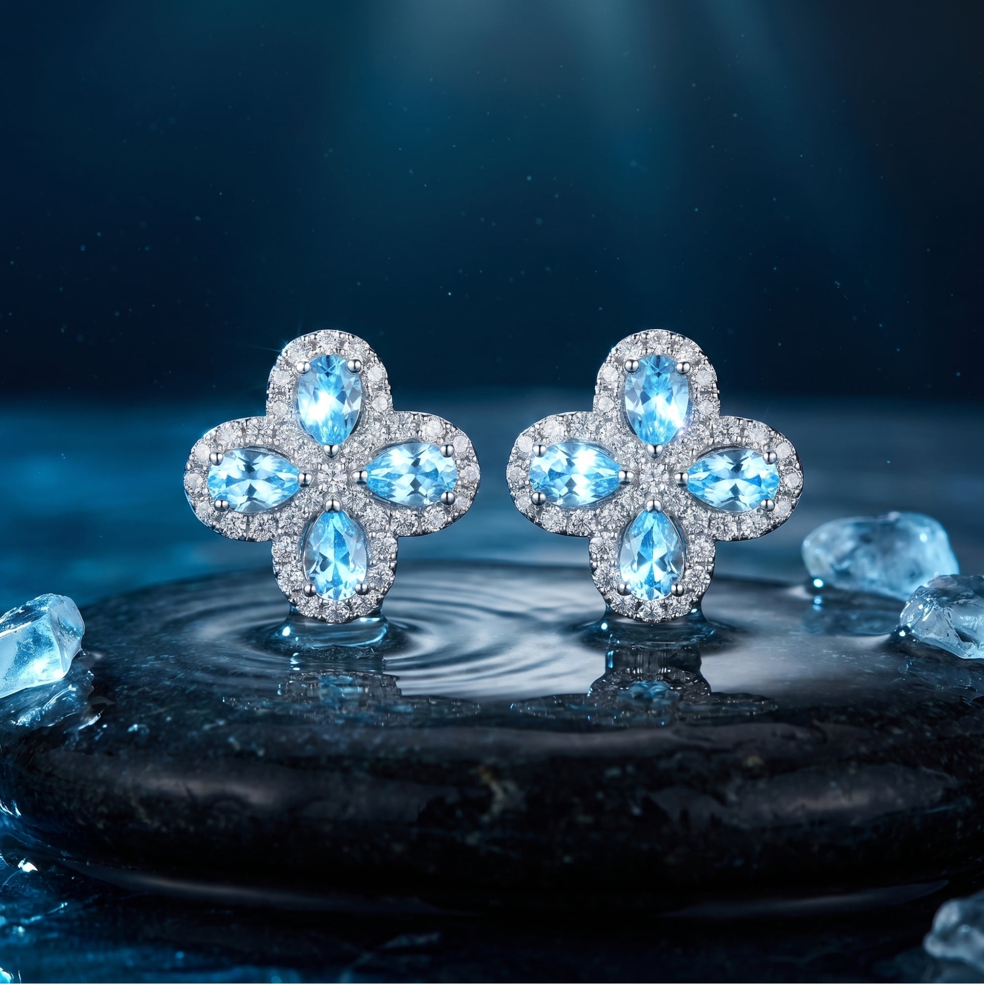 Silver floret cluster earrings with pear cut aquamarine stones on a dark wet stone with water ripples.