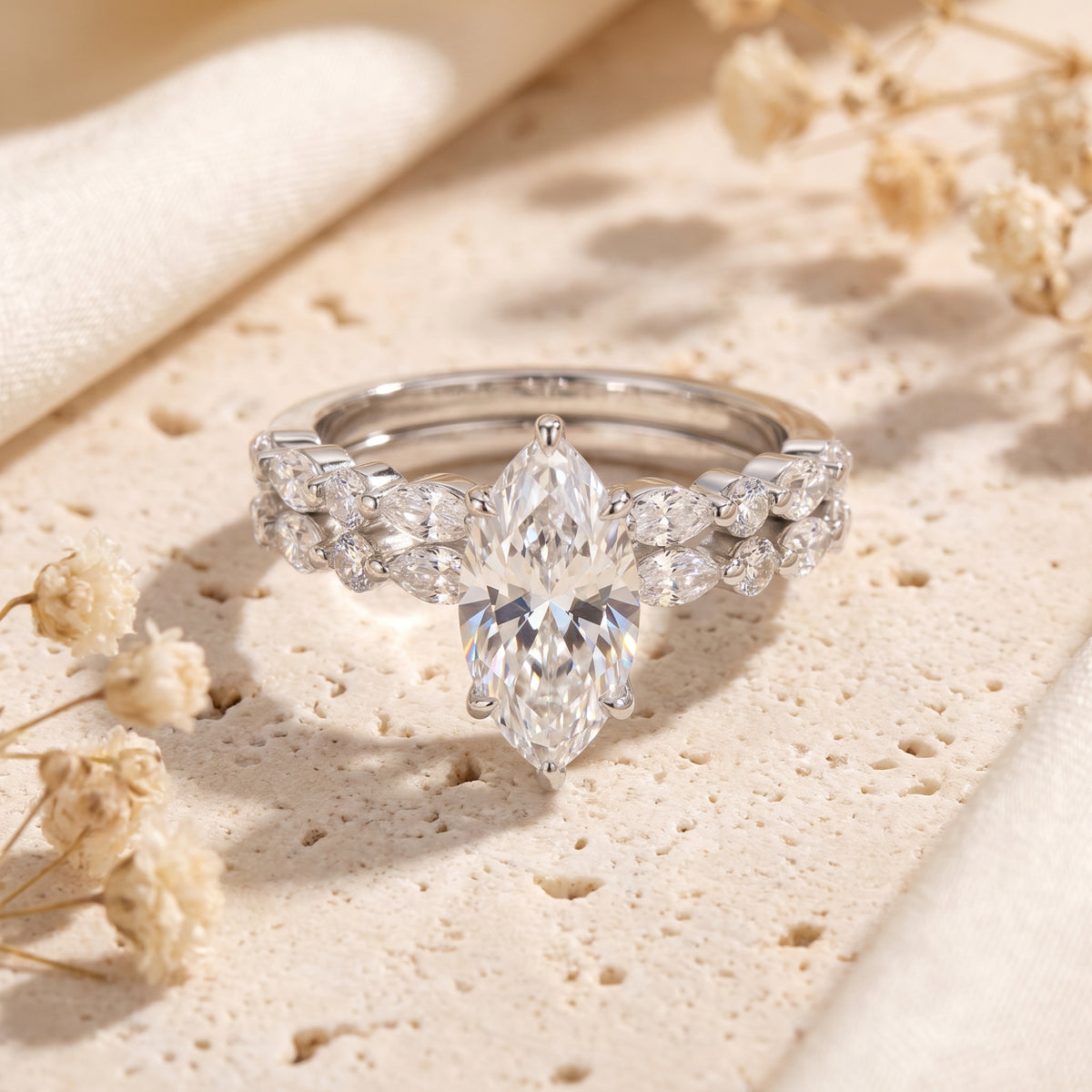 Close-up of a silver ring set with a marquise-cut centerpiece and stone-accented nested bands.