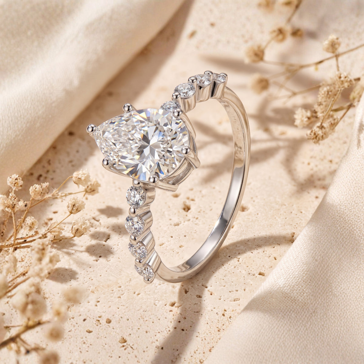 Extreme close-up of a silver ring featuring a faceted pear-cut stone and round accent stones along the band.