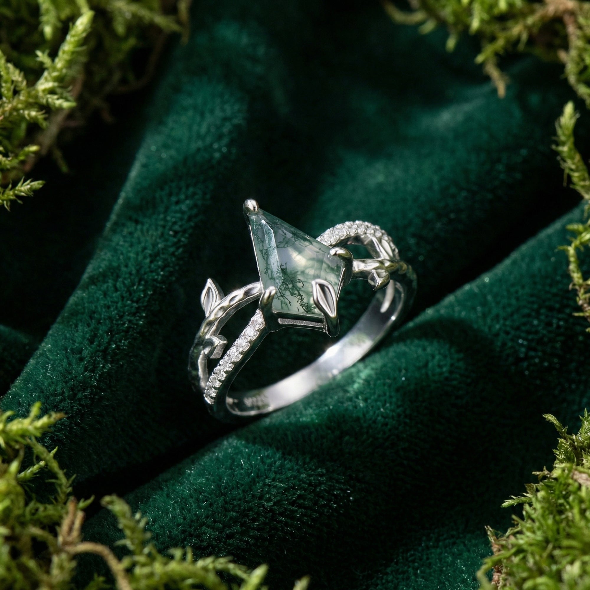 Kite cut moss agate sterling silver ring on dark green velvet surrounded by natural moss.