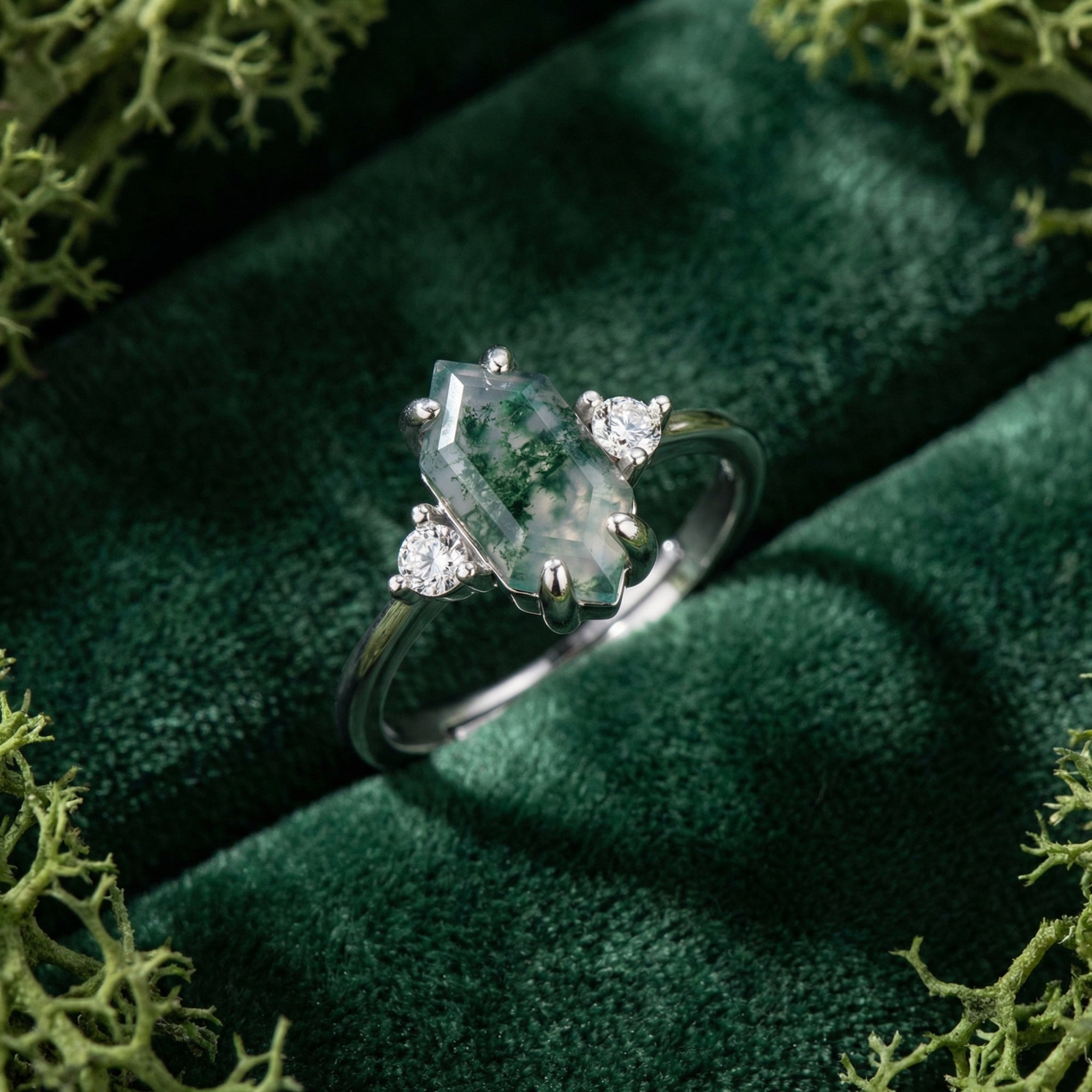Hexagon cut moss agate ring in S925 sterling silver on green velvet with decorative moss.