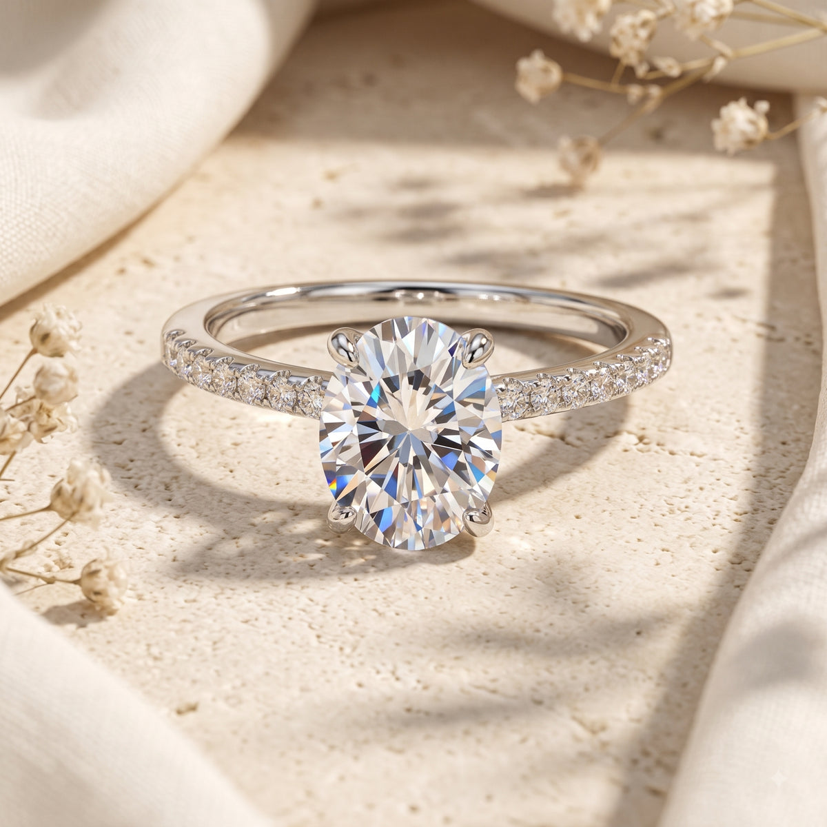 Silver ring with an oval clear center stone and a pavé band, displayed upright on a beige stone surface.