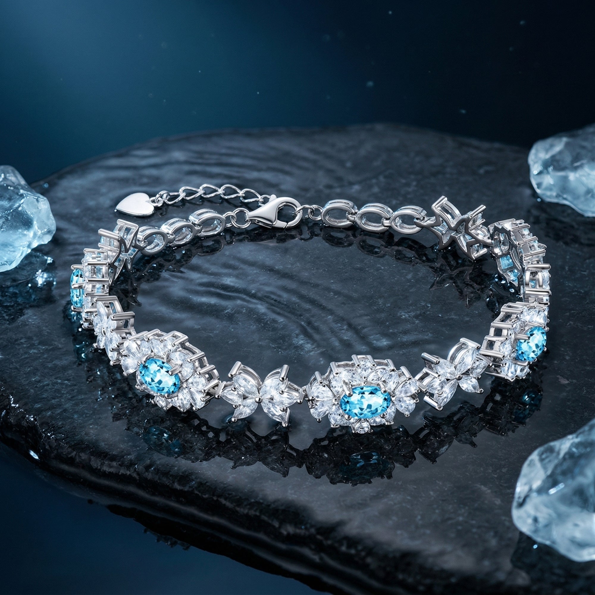 Silver station bracelet with oval aquamarine and marquise stones on a dark, textured stone surface.