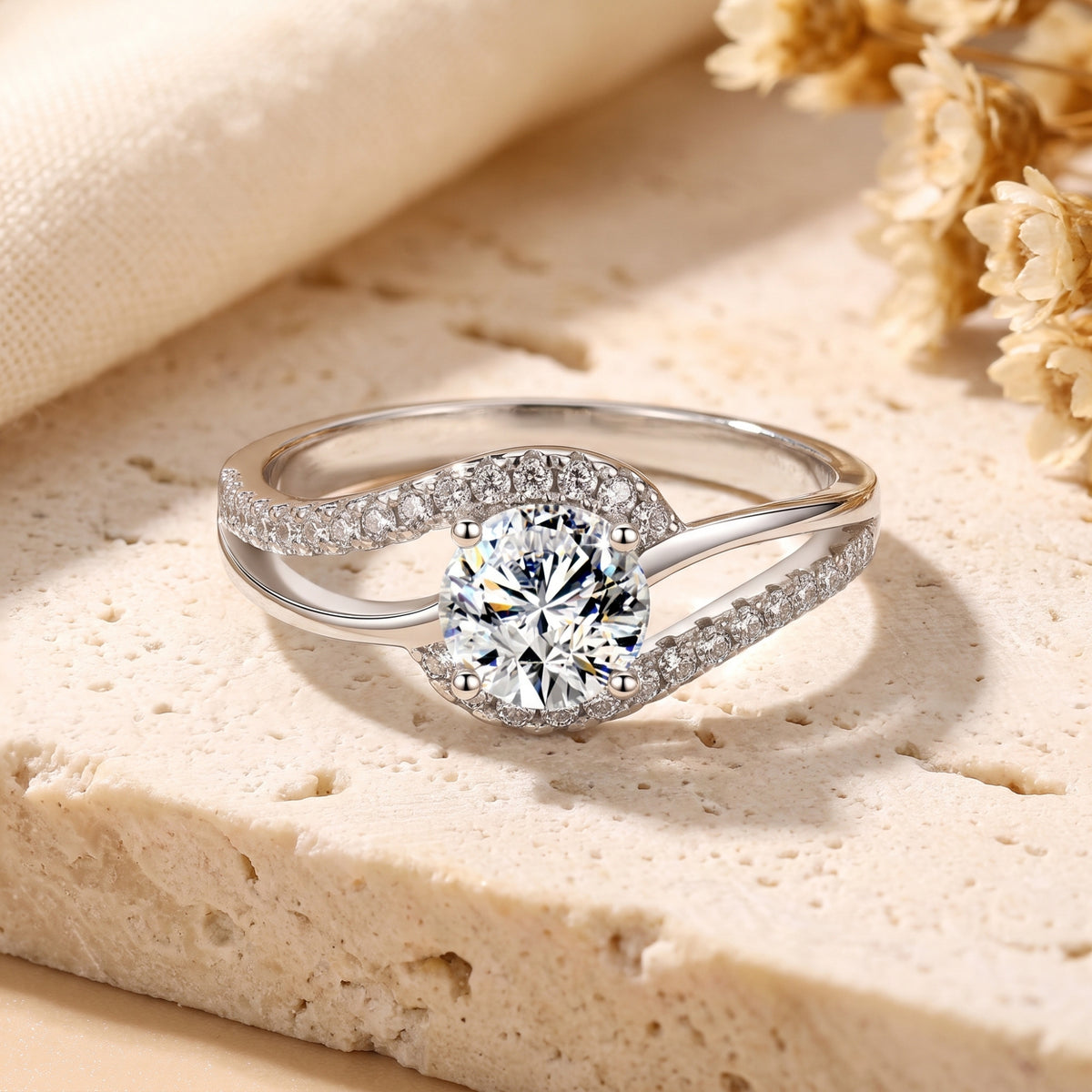 Front view of the silver bypass ring with a round clear center stone and pavé accents resting on stone.