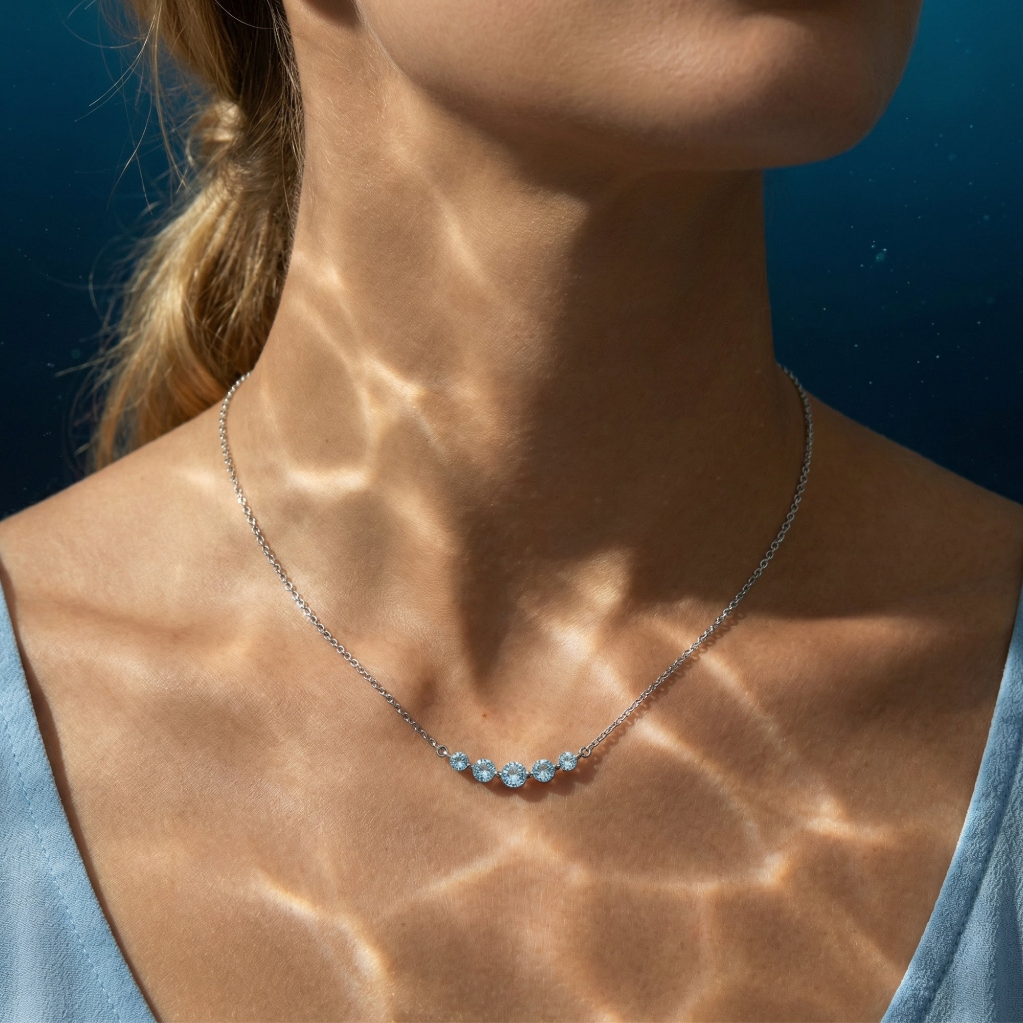 The Ephyra aquamarine necklace in platinum worn by a model with shimmering water reflections.