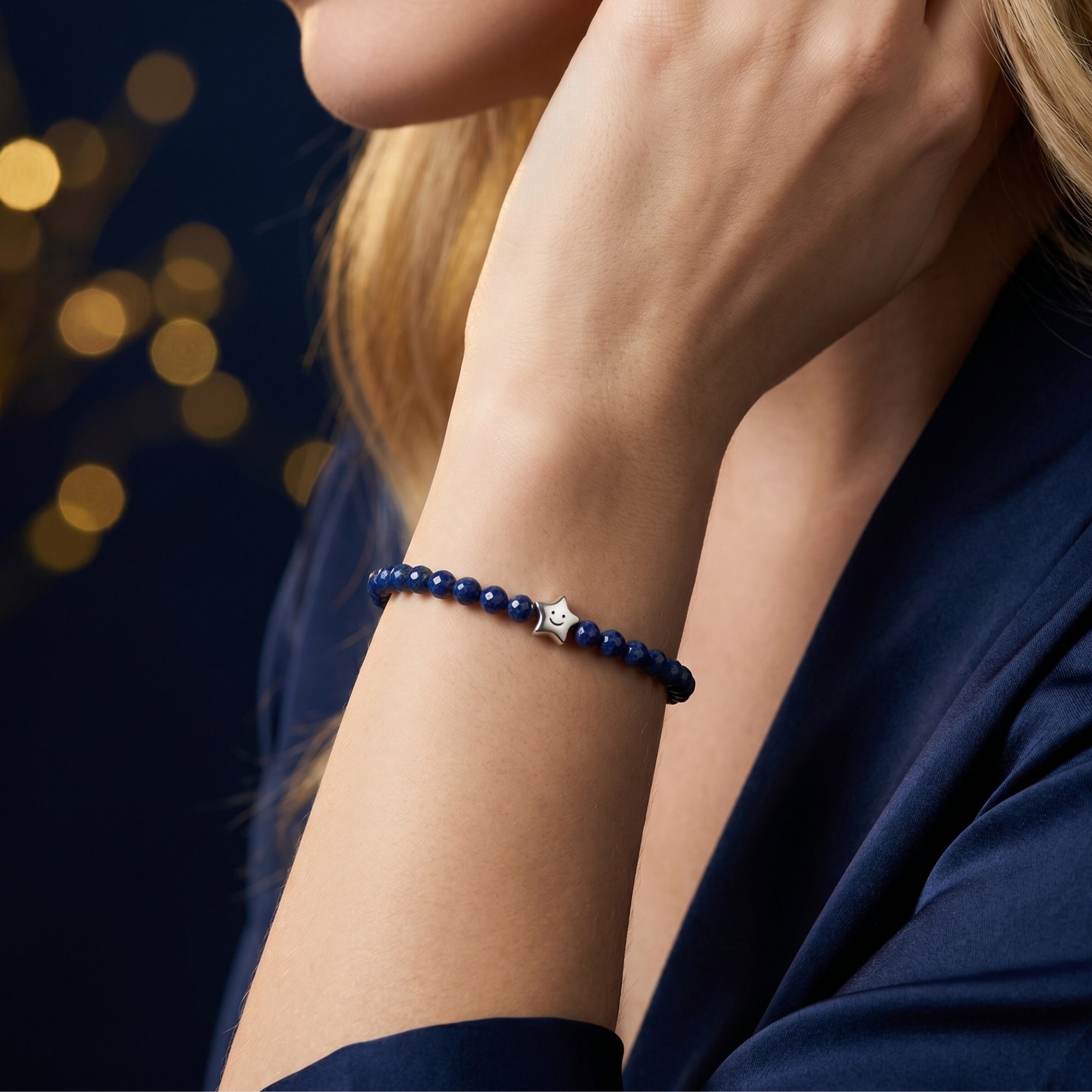 Joyful Star natural lapis bracelet with faceted beads and a silver star charm worn on a woman's wrist.
