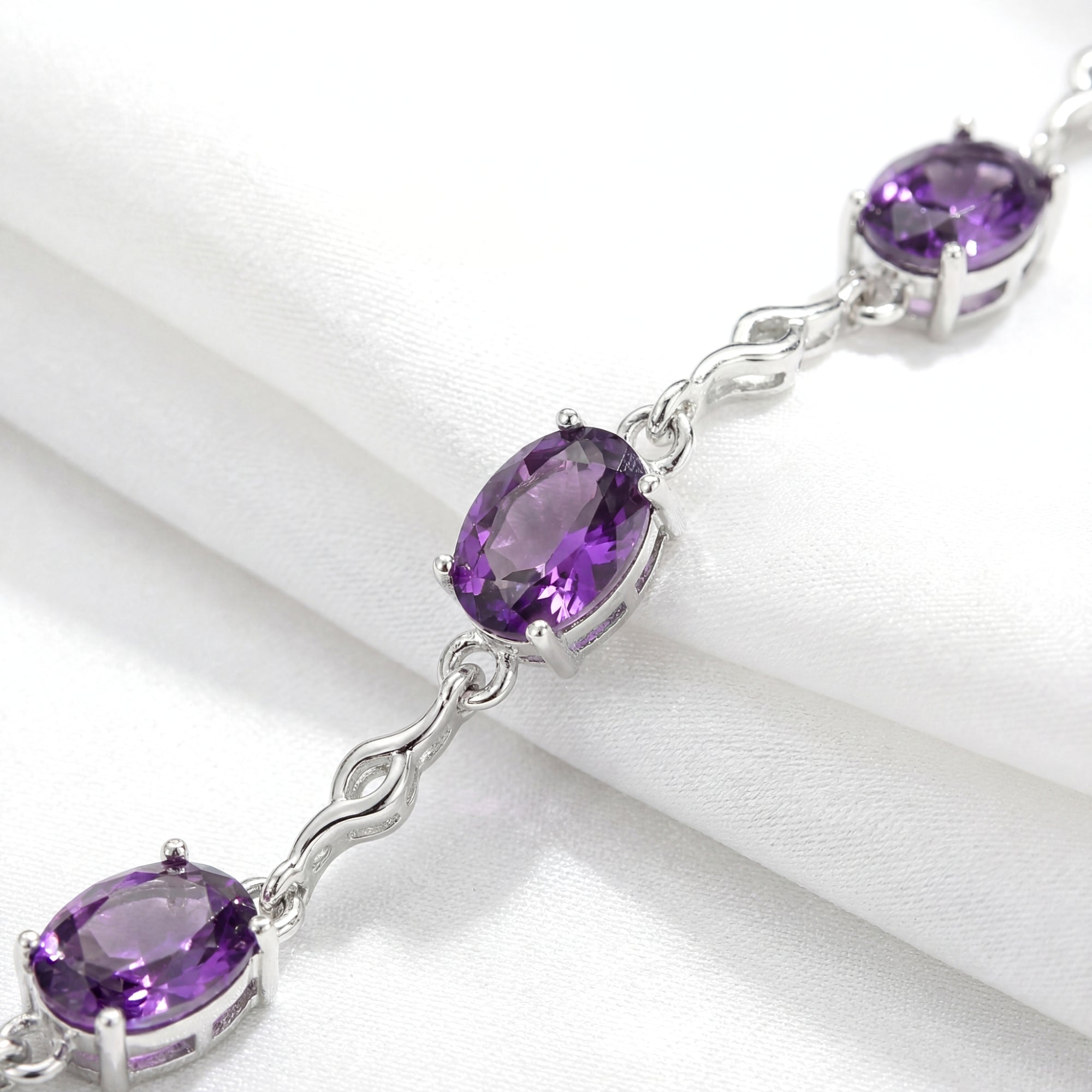 Macro shot of oval-cut simulated amethyst stones in sterling silver prong settings on the Estella station bracelet.