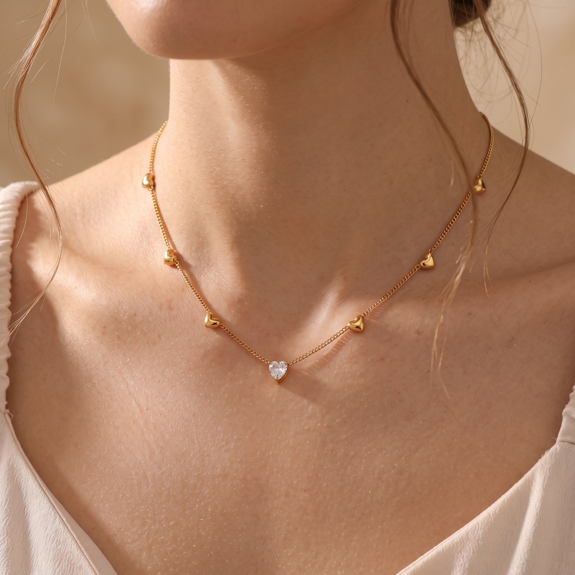 Model wearing the 18K gold Amoris heart necklace featuring a central heart-cut simulated diamond pendant.