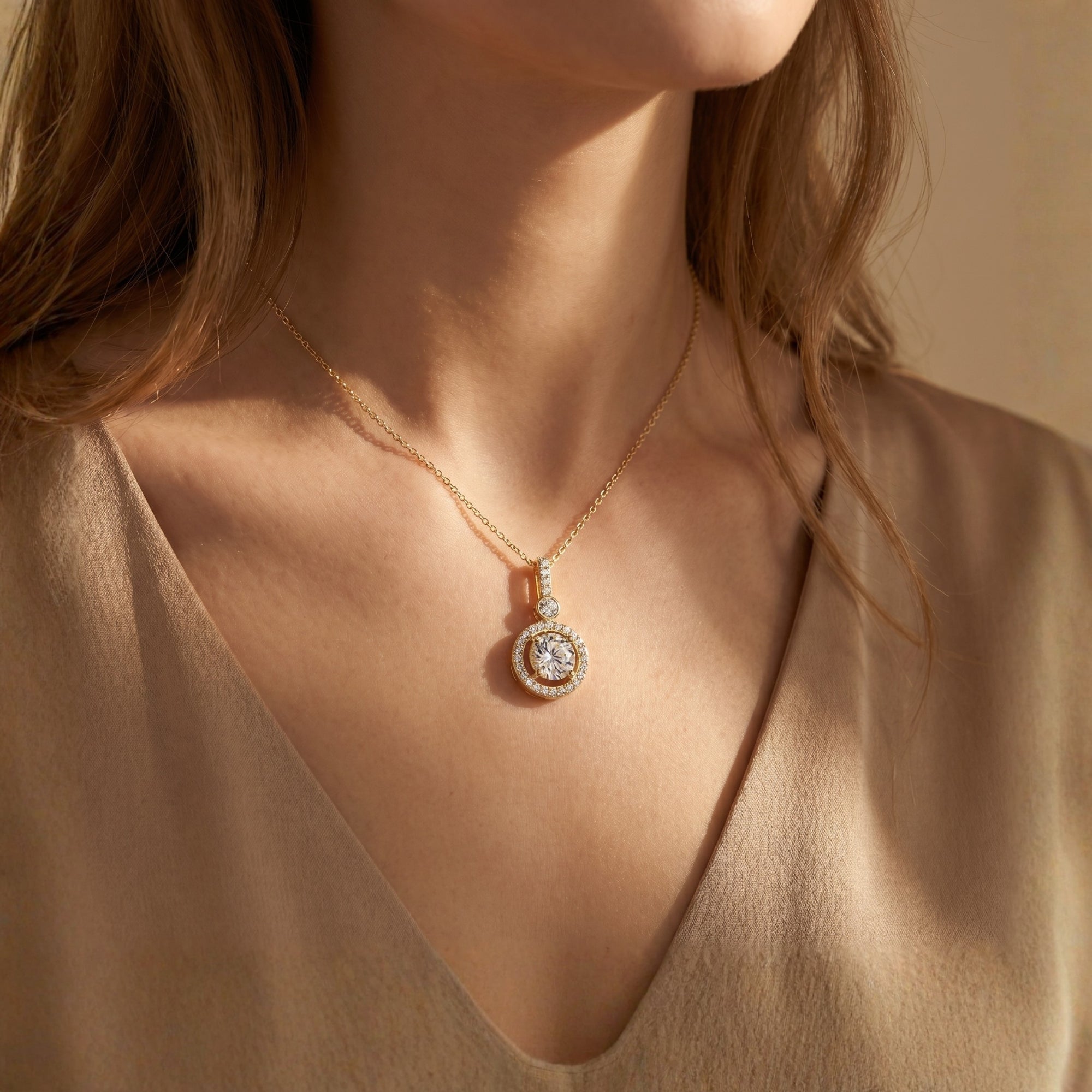 Woman wearing the gold Antoinette moissanite halo pendant necklace with a round cut center stone.