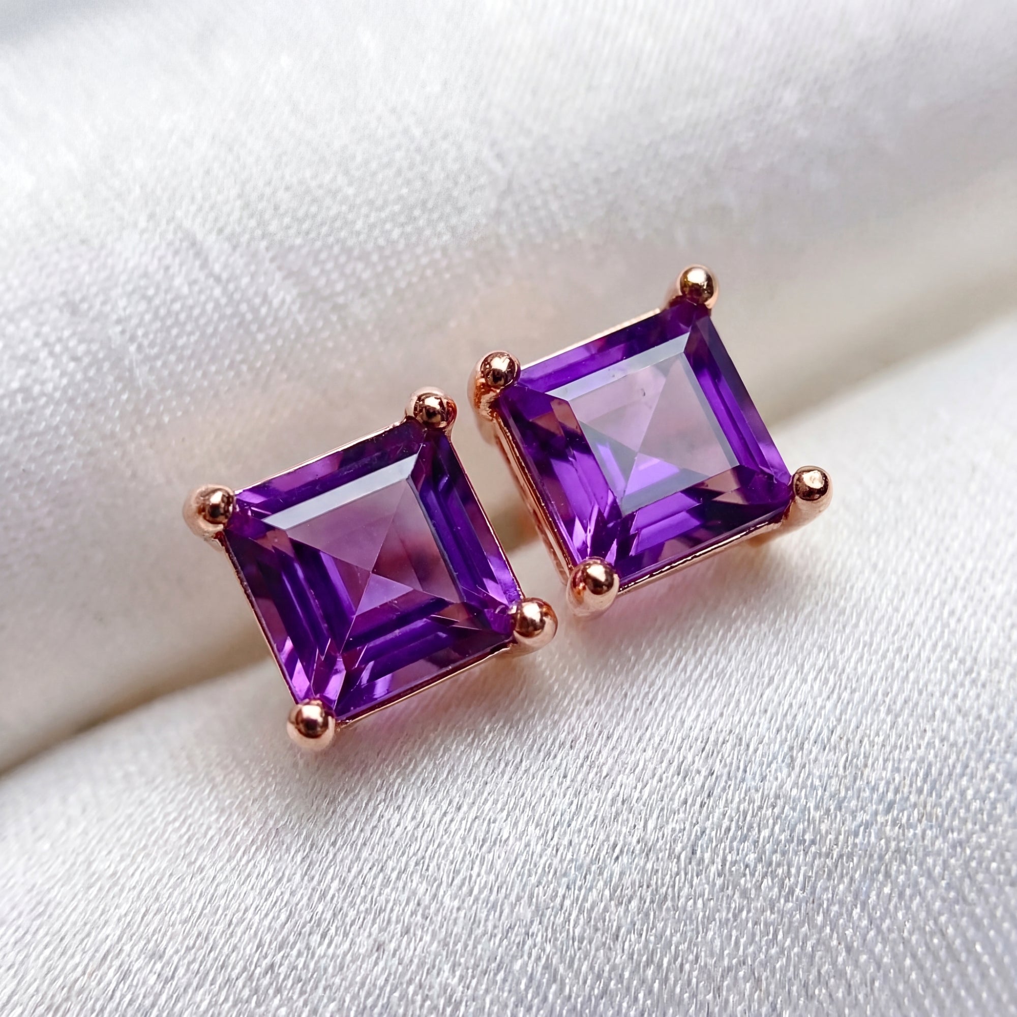 Macro view of square cut simulated amethyst stud earrings in 18K rose gold vermeil settings.