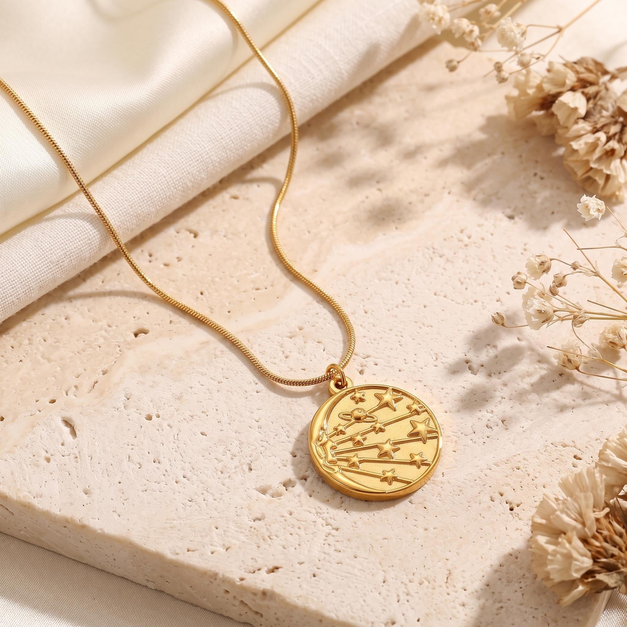 Close-up of the 18K gold celestial medallion pendant with star details on stone.