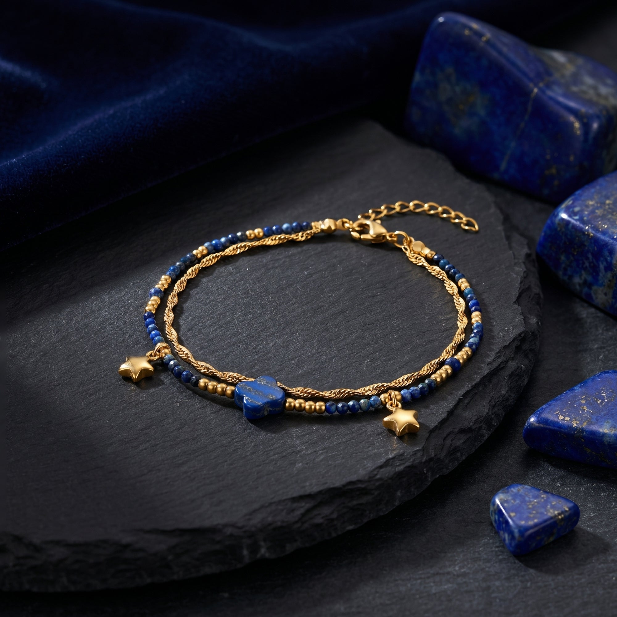 Side view of the gold plated stainless steel bracelet with 3mm natural lapis beads and clover-shaped stone on a black slate.