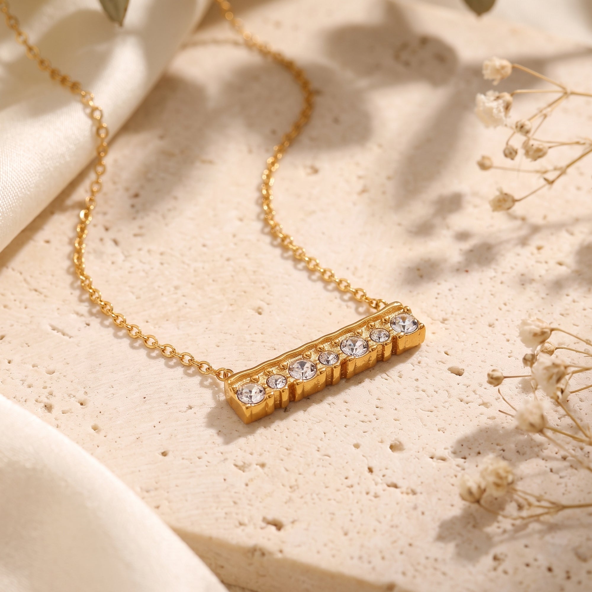 Close-up of the textured 18K gold finish bar pendant with seven brilliant-cut simulated diamond stones.