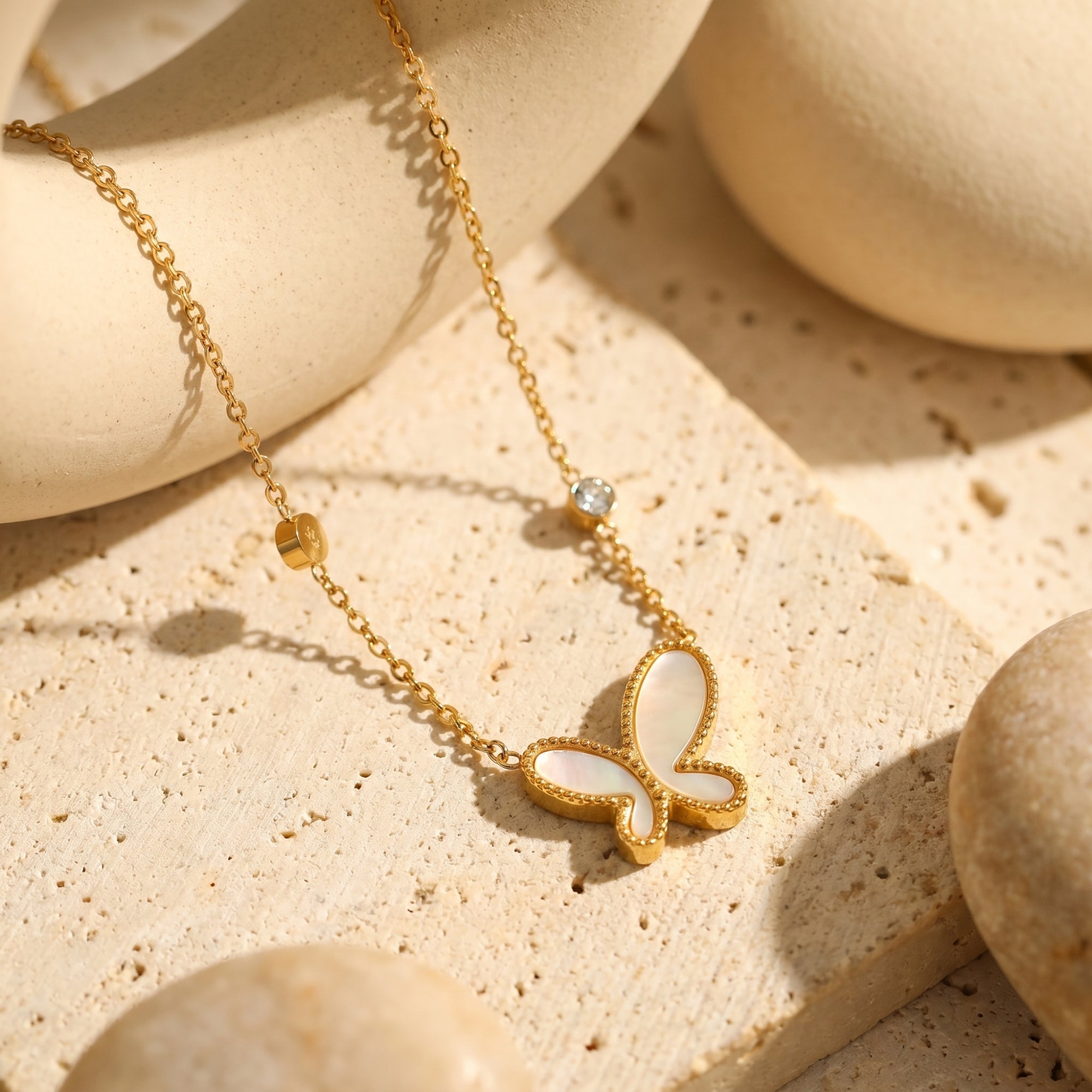 Close-up of a gold butterfly pendant featuring mother of pearl inlay on stone.