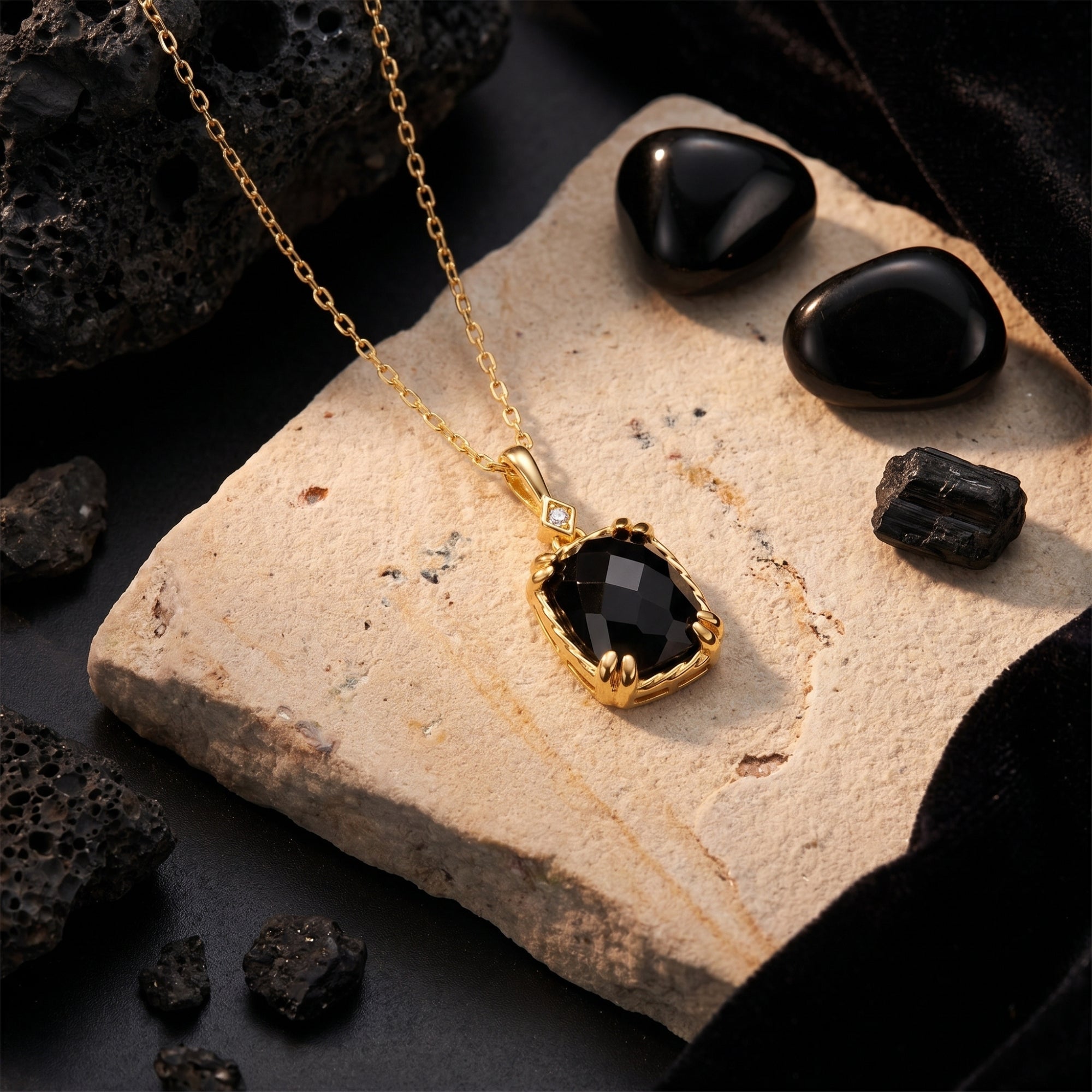 Close-up of the faceted cushion-cut black onyx pendant and yellow gold setting resting on a stone.