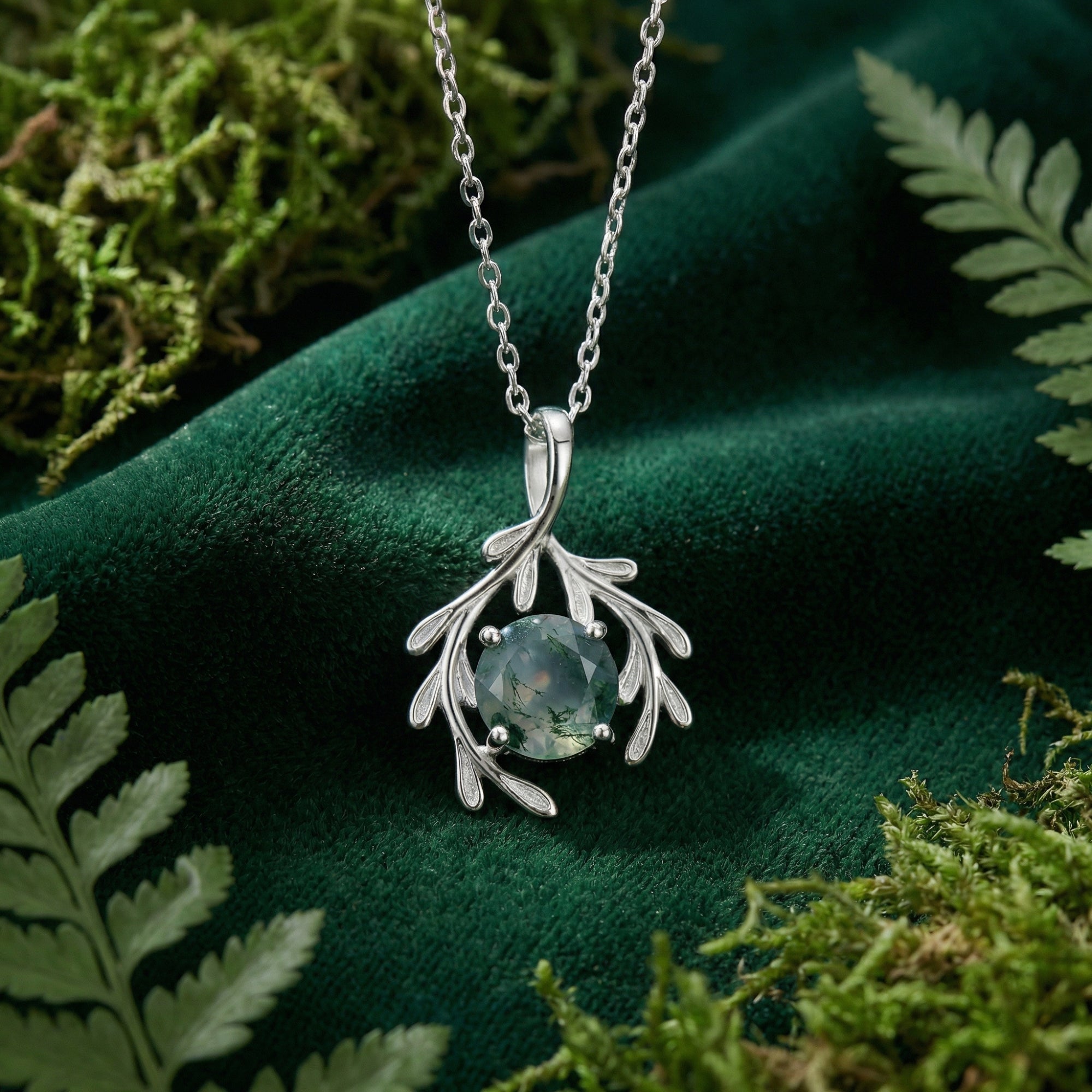 Sterling silver botanical moss agate pendant necklace displayed on green velvet with natural moss and ferns.