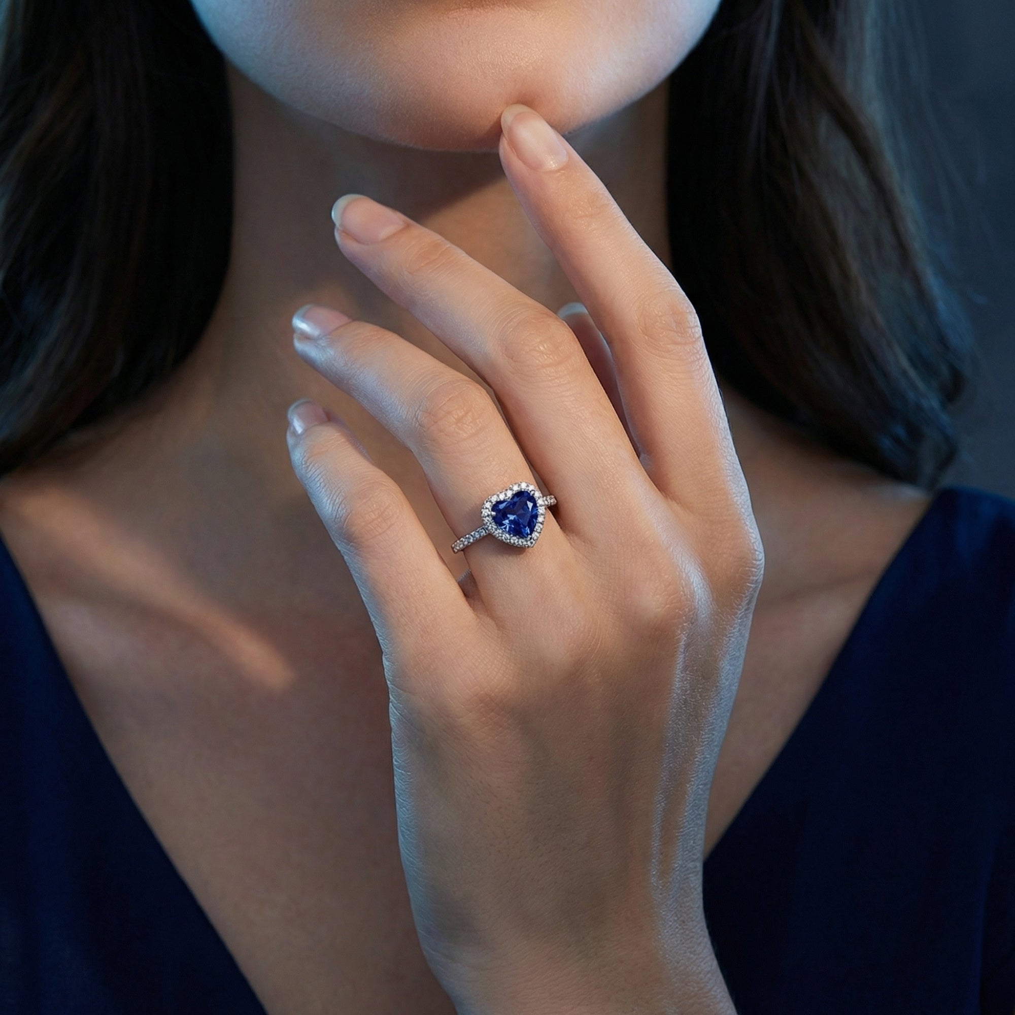 Woman wearing the Vesperia heart tanzanite halo ring in silver, paired with a navy blue dress.