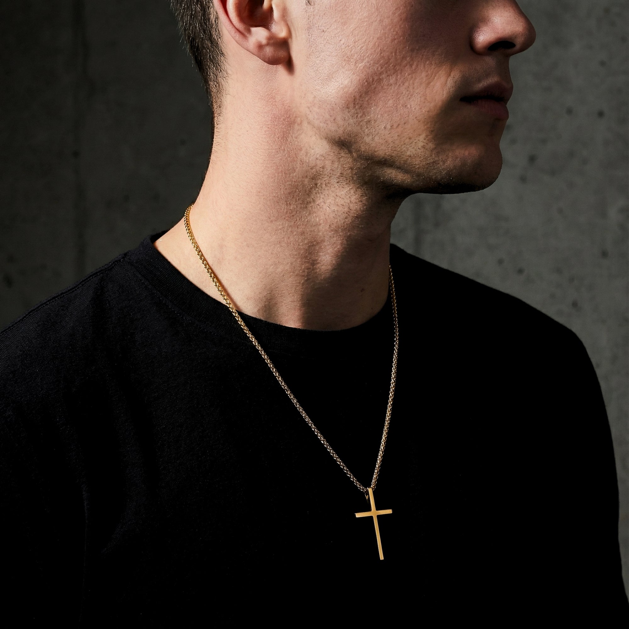 Side profile of a man wearing the gold tone stainless steel cross pendant necklace with a box chain.