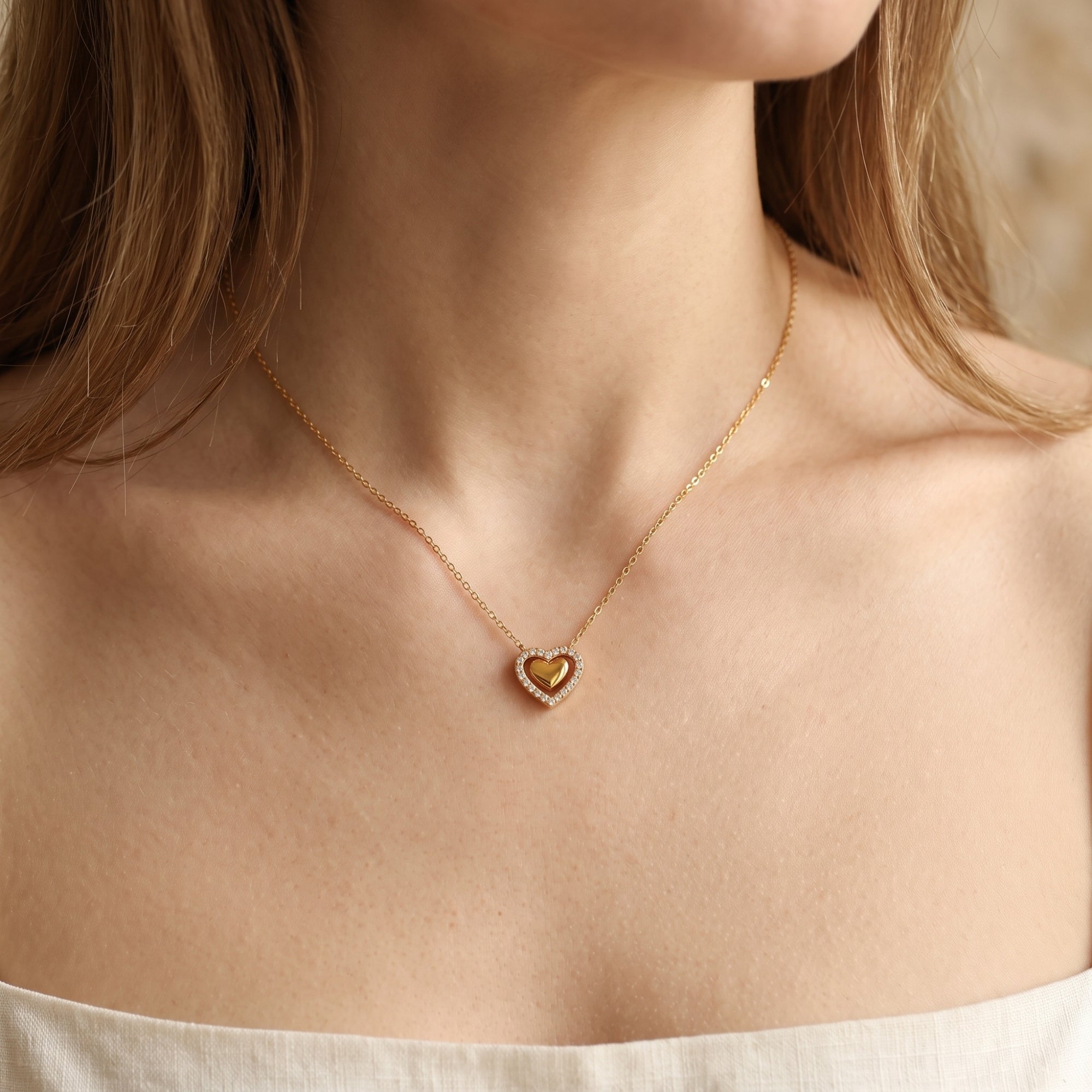 Front view of a model wearing the gold Priscilla heart pendant necklace with a cubic zirconia halo.
