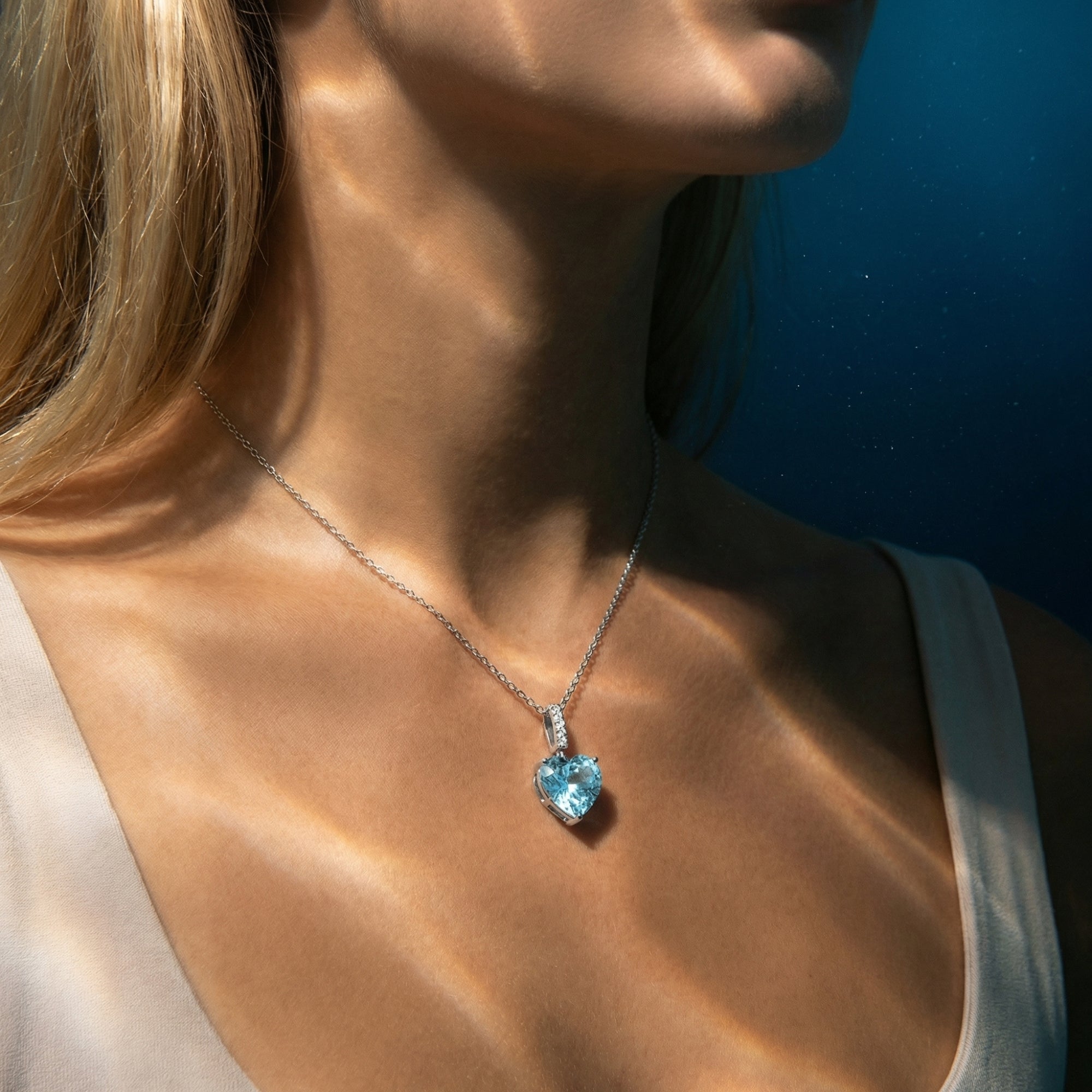 Model wearing the heart cut aquamarine platinum necklace, captured from a side angle in soft natural light.