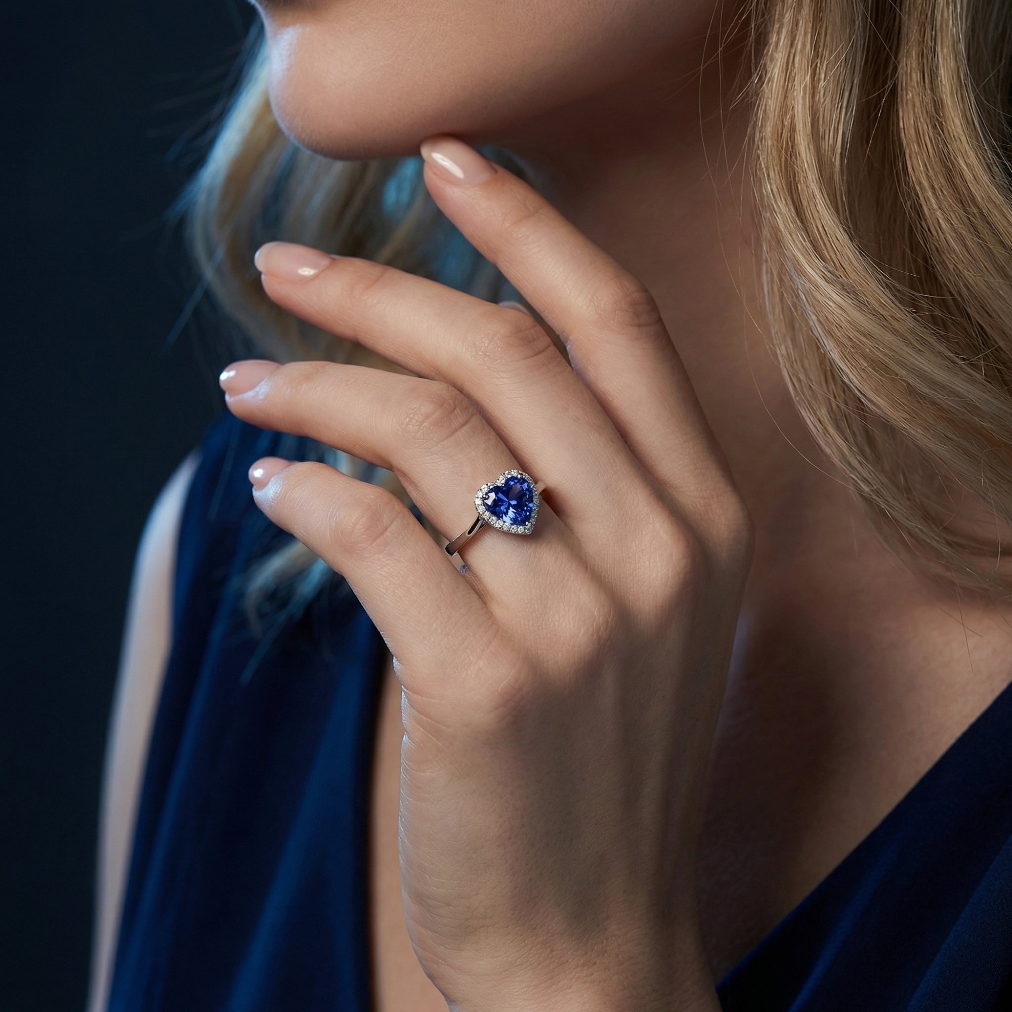 Sterling silver heart tanzanite ring worn by a model, showcasing the brilliant blue gemstone and halo design.