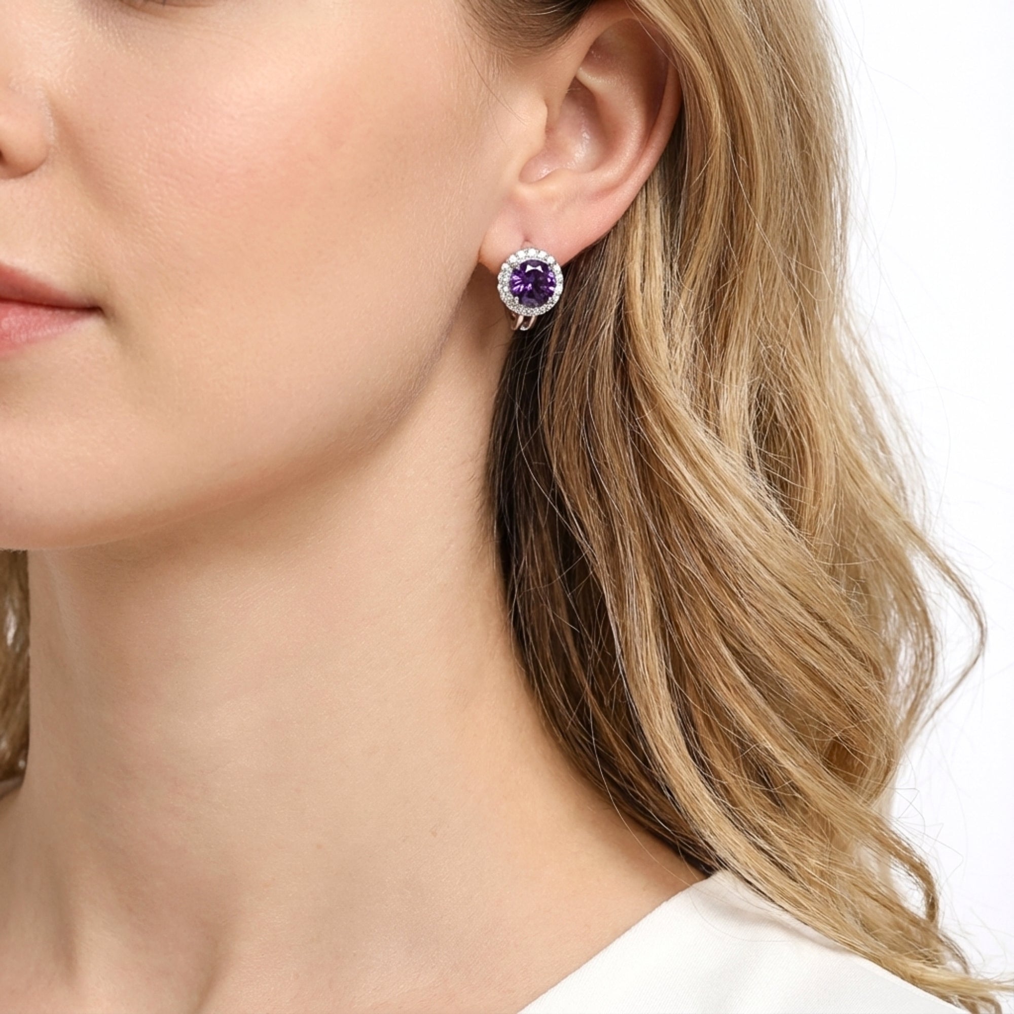 Close-up view of a purple moissanite halo stud earring in sterling silver on a woman's ear.