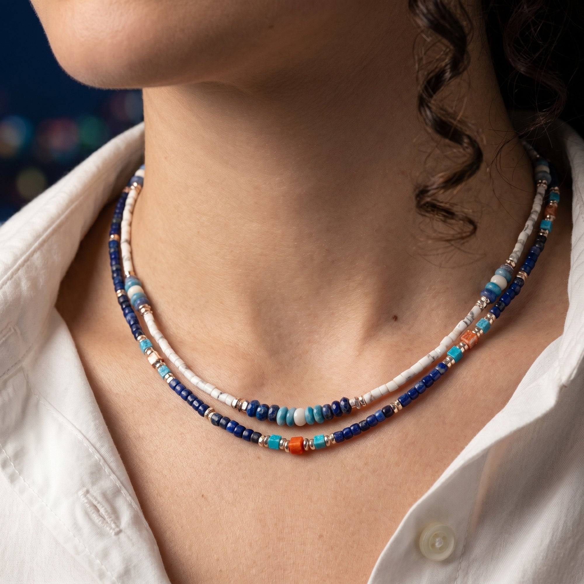Close-up of the layered Altair lapis lazuli bead necklace with gold-toned spacers worn by a model.