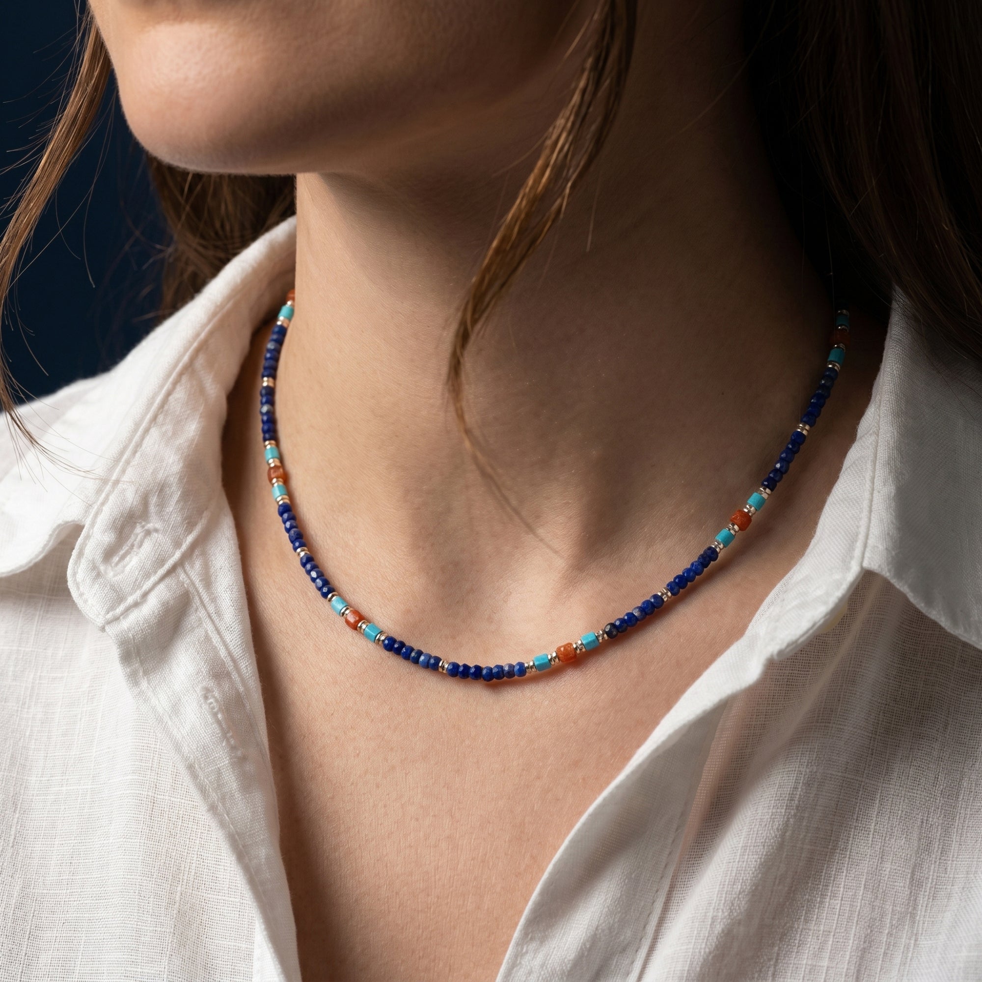 Close-up of the Starfall 5mm lapis, turquoise, and orange beaded necklace with gold spacers on a model.