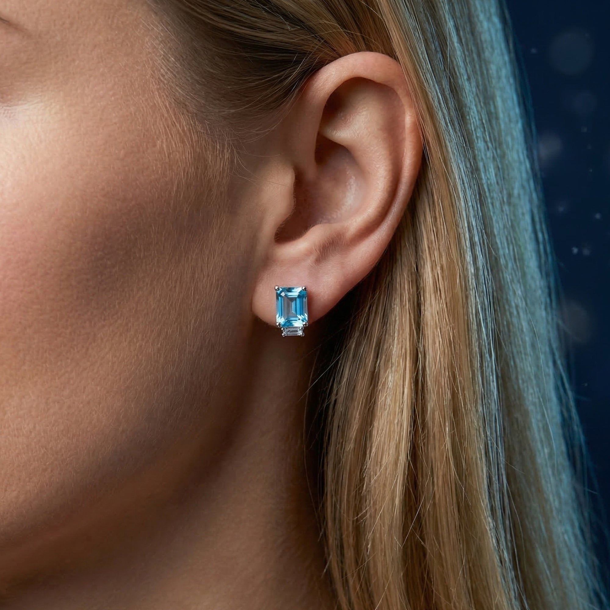 Model wearing a Swiss blue topaz emerald cut earring in white gold, showcasing the vibrant oceanic hue.