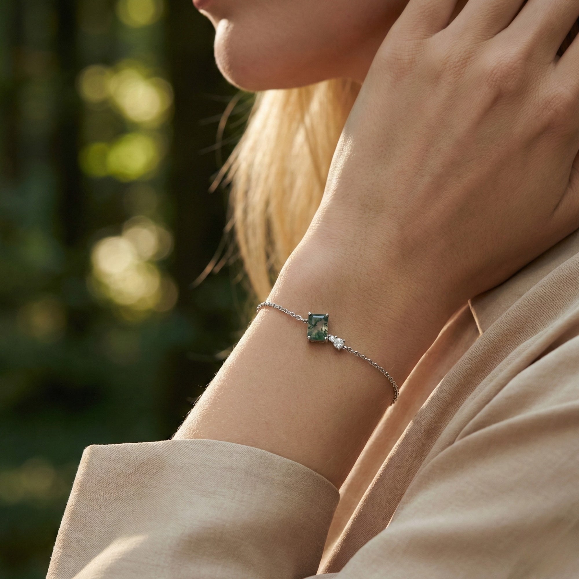 Square cut moss agate charm bracelet in S925 sterling silver shown on a model's wrist against a soft outdoor background.