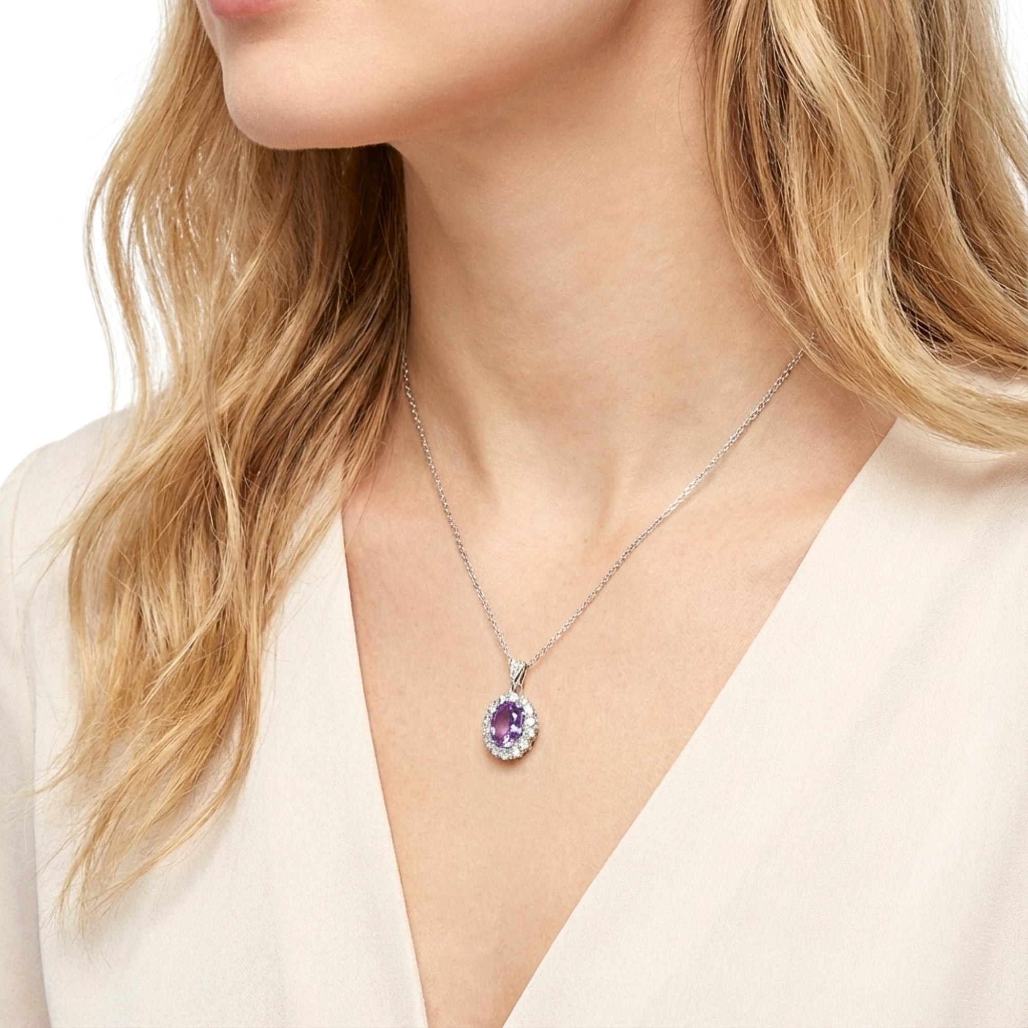 Angled view of a model wearing an oval simulated amethyst halo necklace in sterling silver.