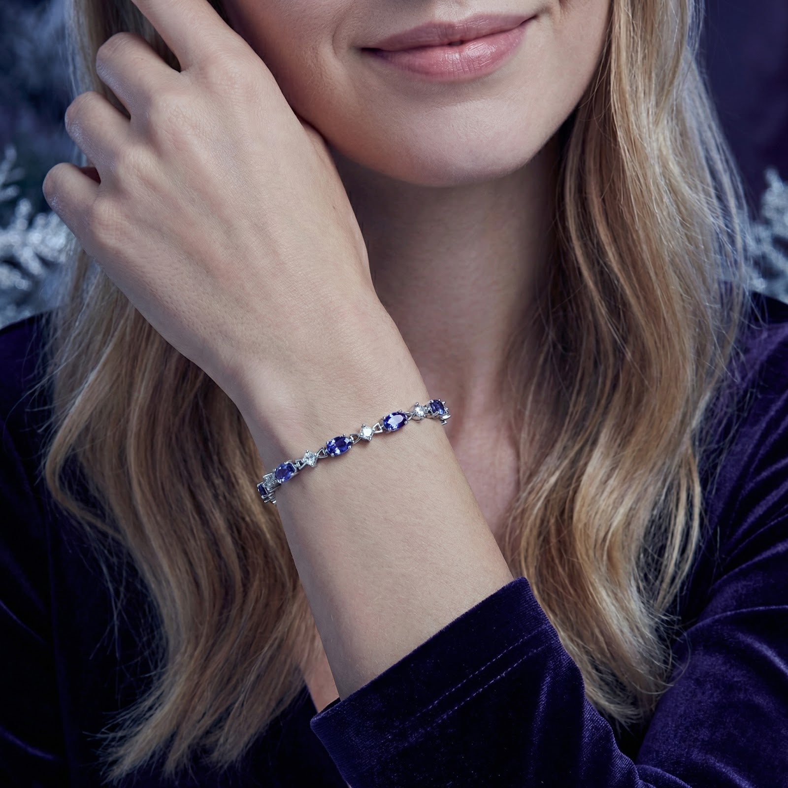 Woman wearing the Zenelle sterling silver station bracelet with oval-cut simulated tanzanite stones on her wrist.