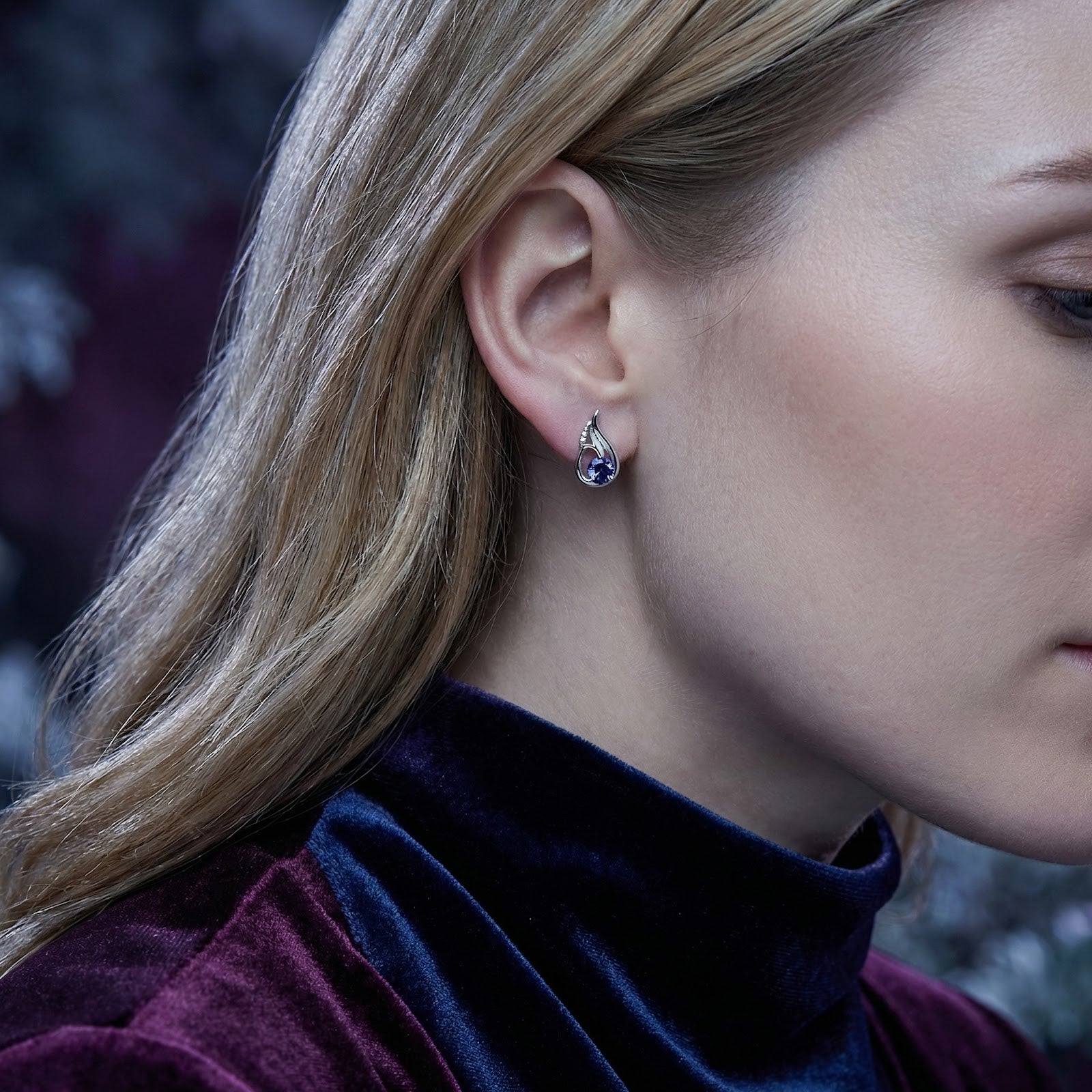 Side view of a model wearing the sterling silver Florisara Bud earring with a brilliant blue simulated tanzanite.