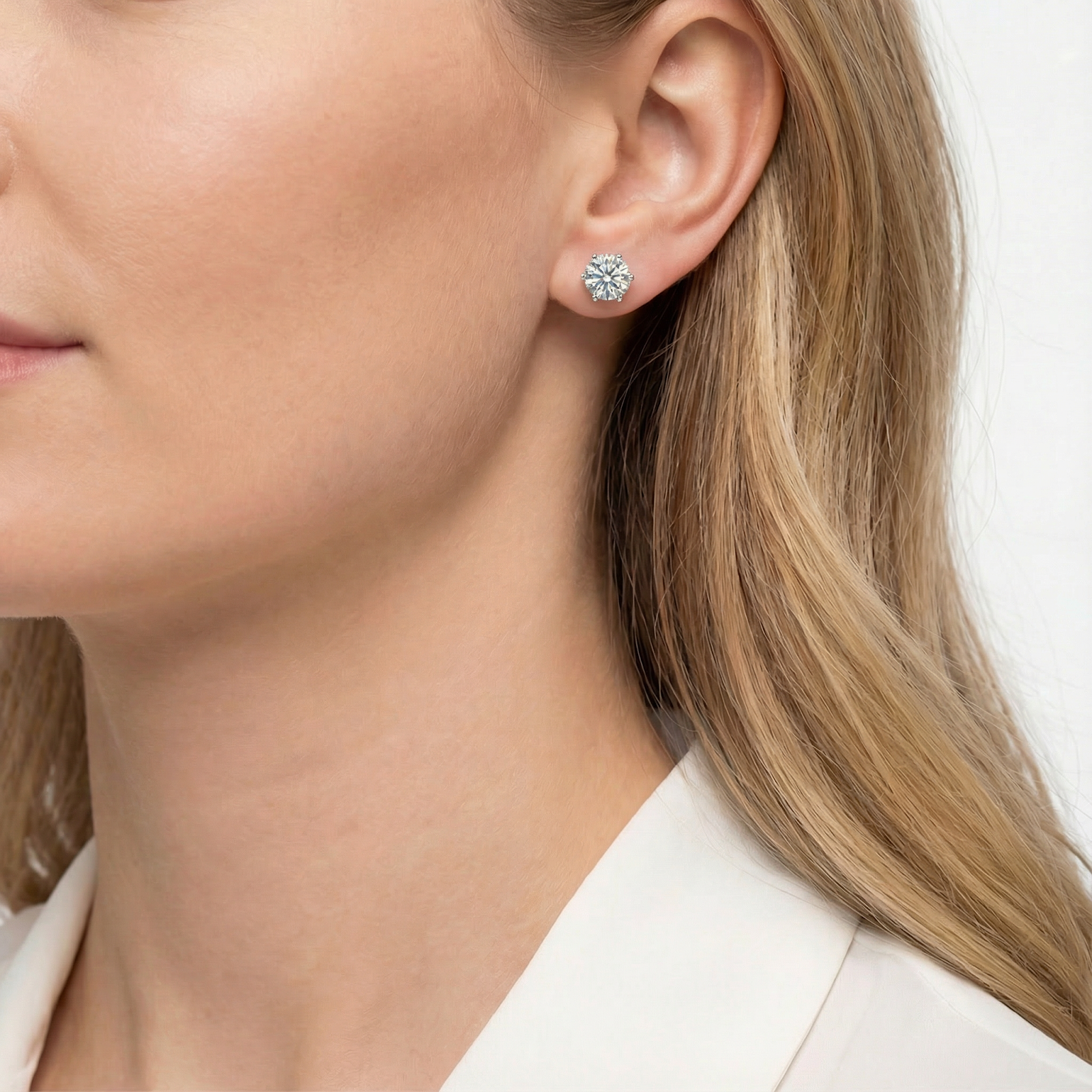 Side view of a woman wearing a round cut simulated diamond stud earring in sterling silver.