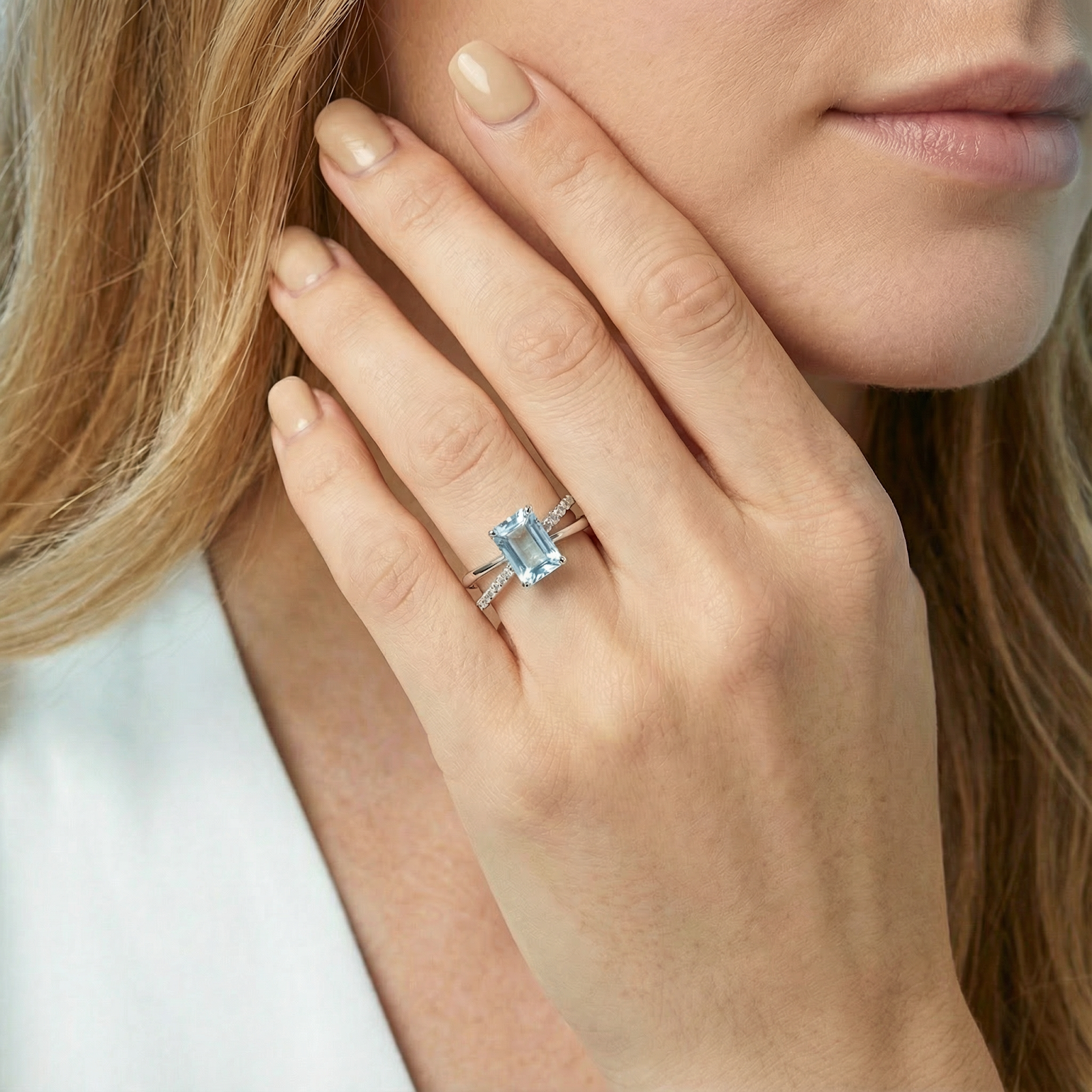 Emerald cut simulated aquamarine twist ring in S925 sterling silver worn on a woman's hand.