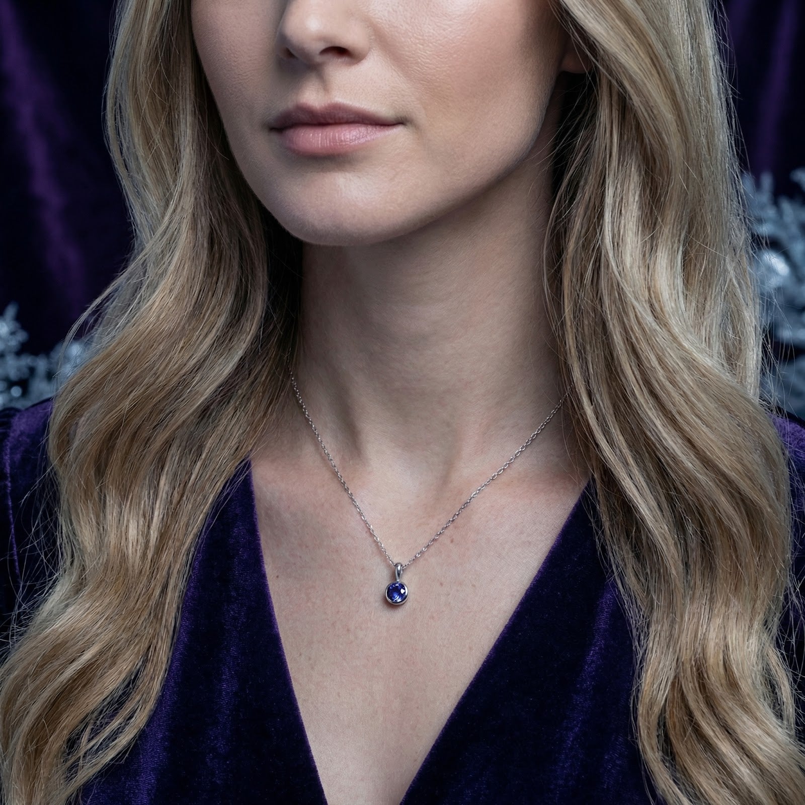 Model wearing the silver Neriselle solitaire necklace with a deep blue-violet simulated tanzanite stone.