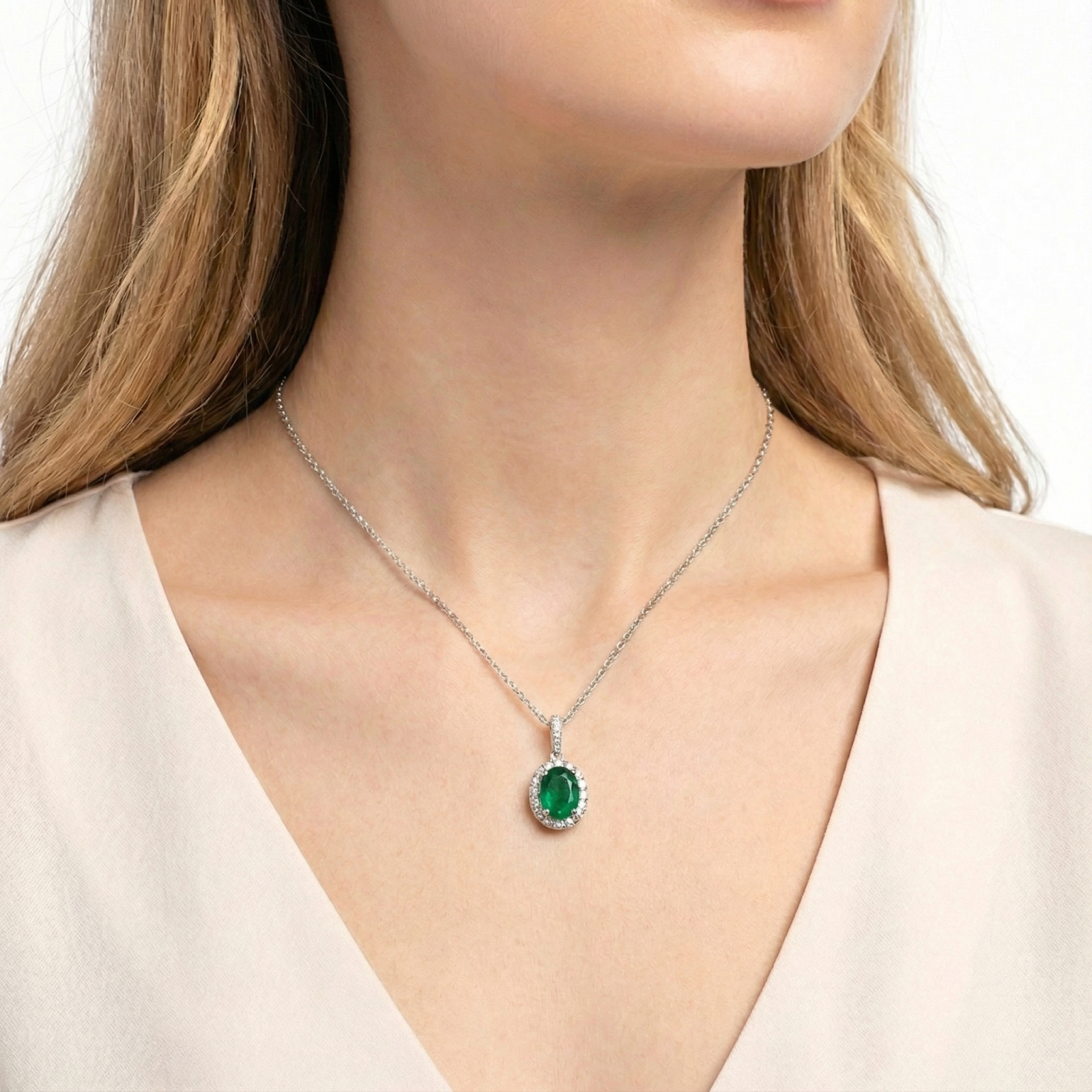 Woman wearing the oval simulated emerald halo pendant on a sterling silver chain against a cream blouse.