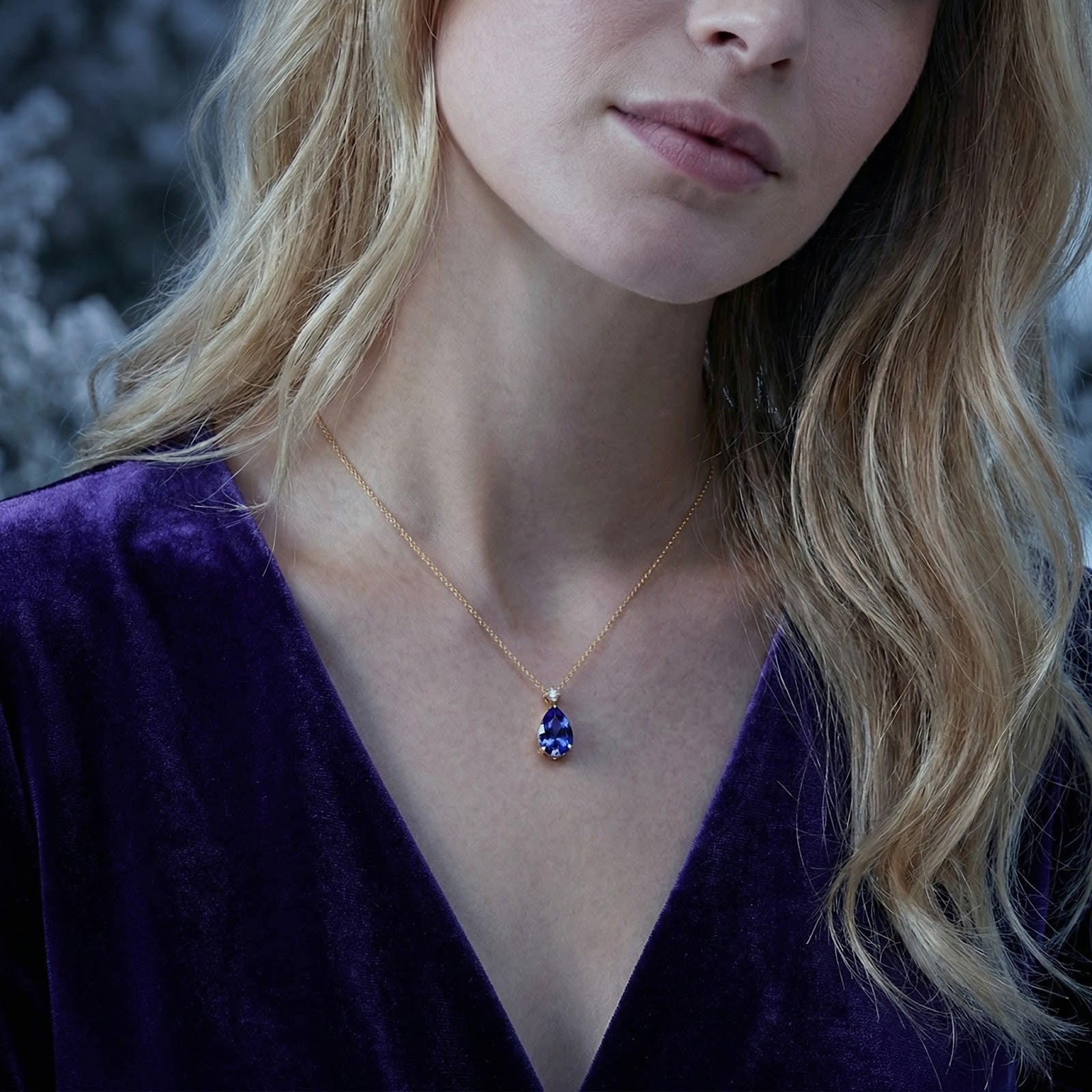 Model wearing the 18K gold vermeil necklace featuring a teardrop-cut blue-violet simulated tanzanite.