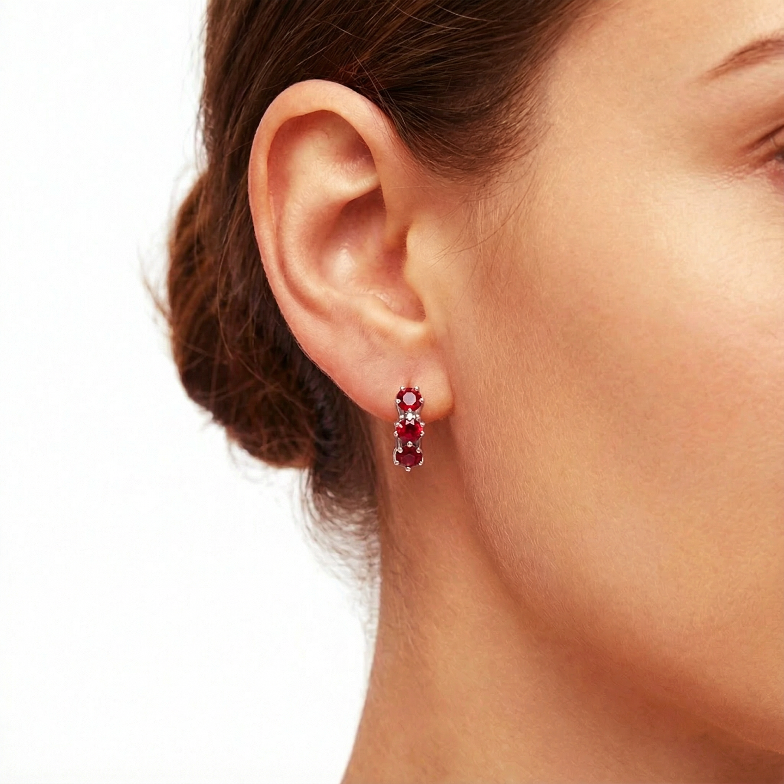 Close-up of a model wearing a star-cut simulated ruby huggie earring in S925 sterling silver.