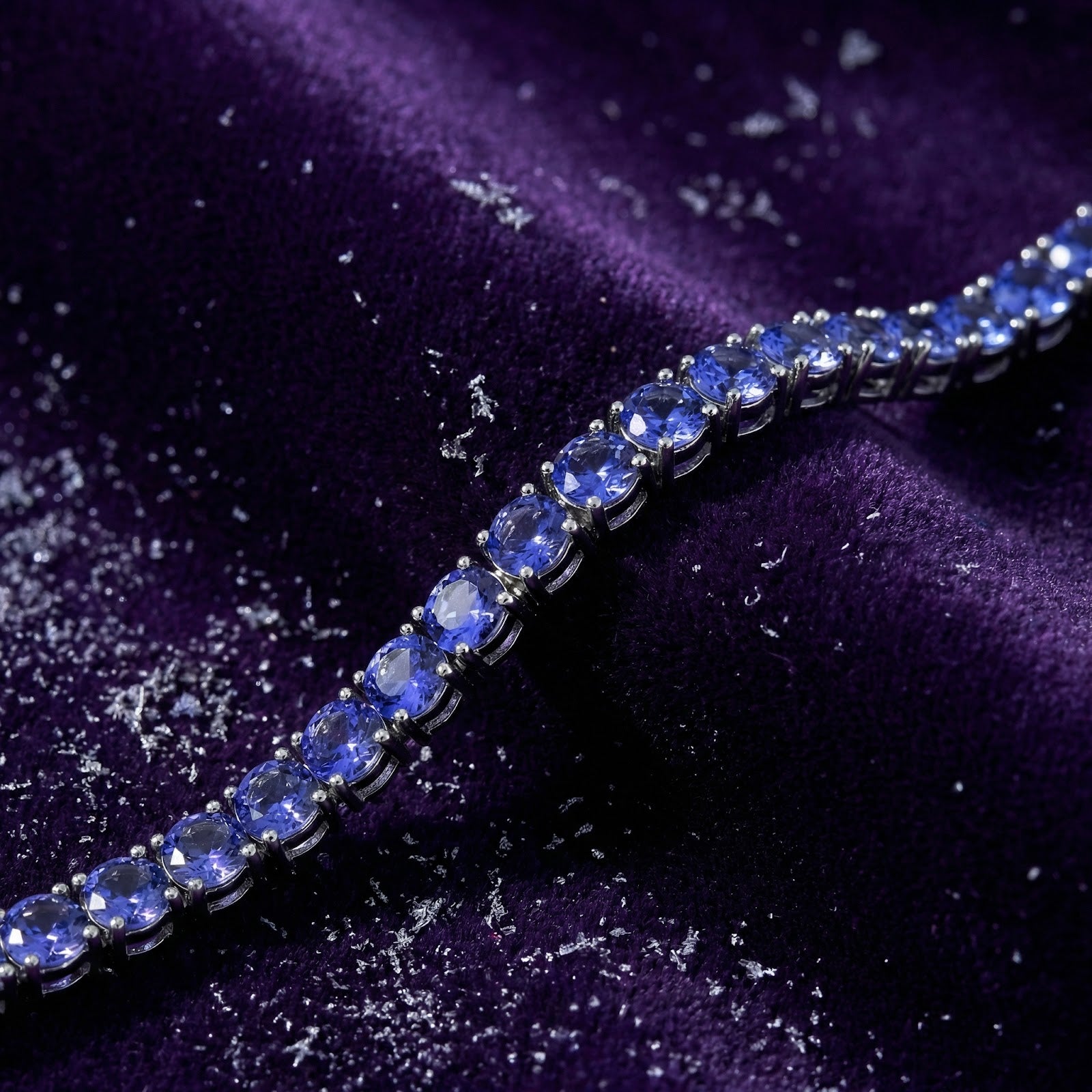 Macro view of round cut simulated tanzanite stones in a stainless steel tennis bracelet setting.
