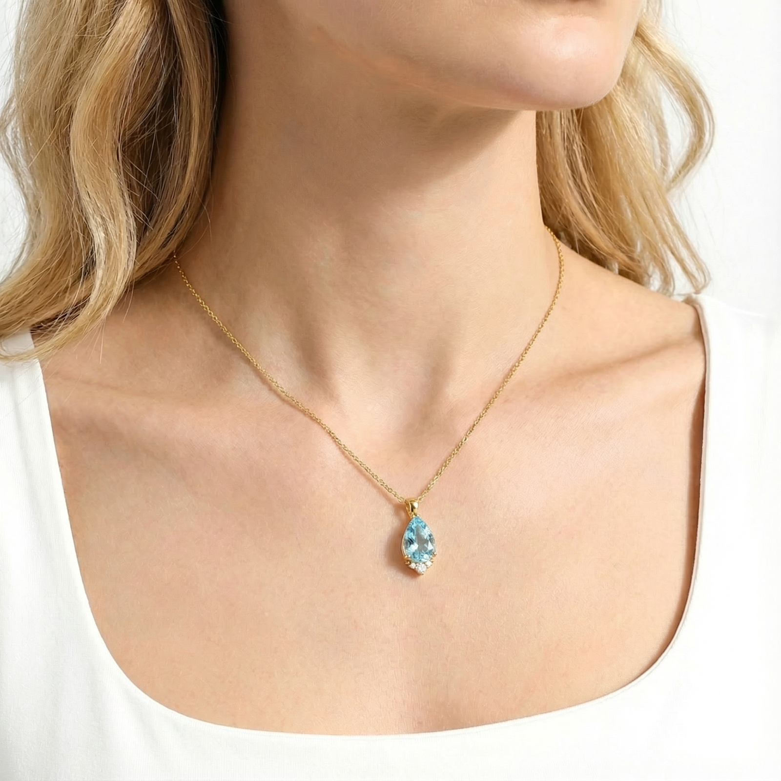 Close-up of the pear cut simulated aquamarine gold vermeil necklace worn on a model.