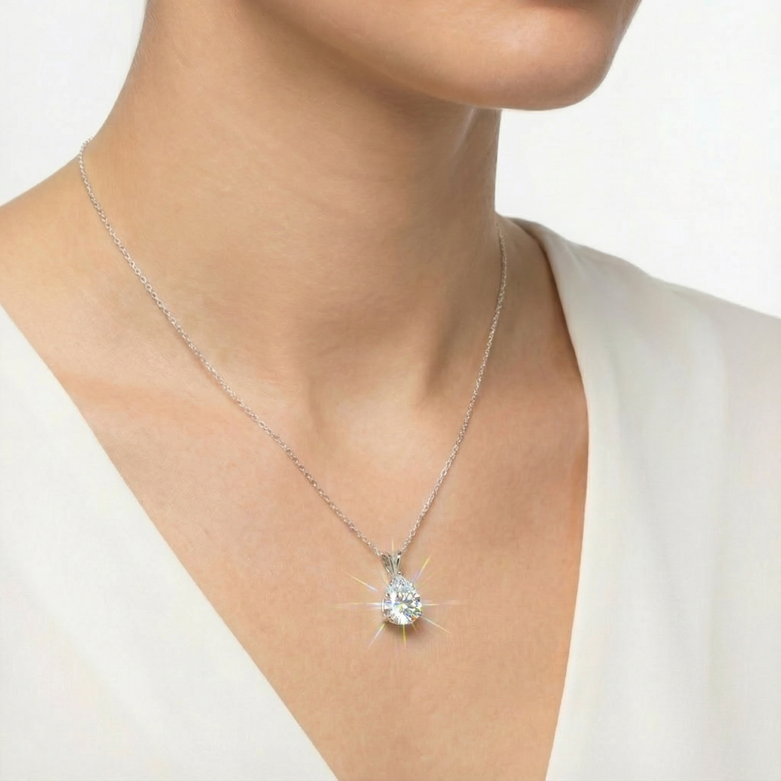Angled view of a woman wearing a 1.5CT pear-cut moissanite birthstone necklace in white gold or sterling silver.