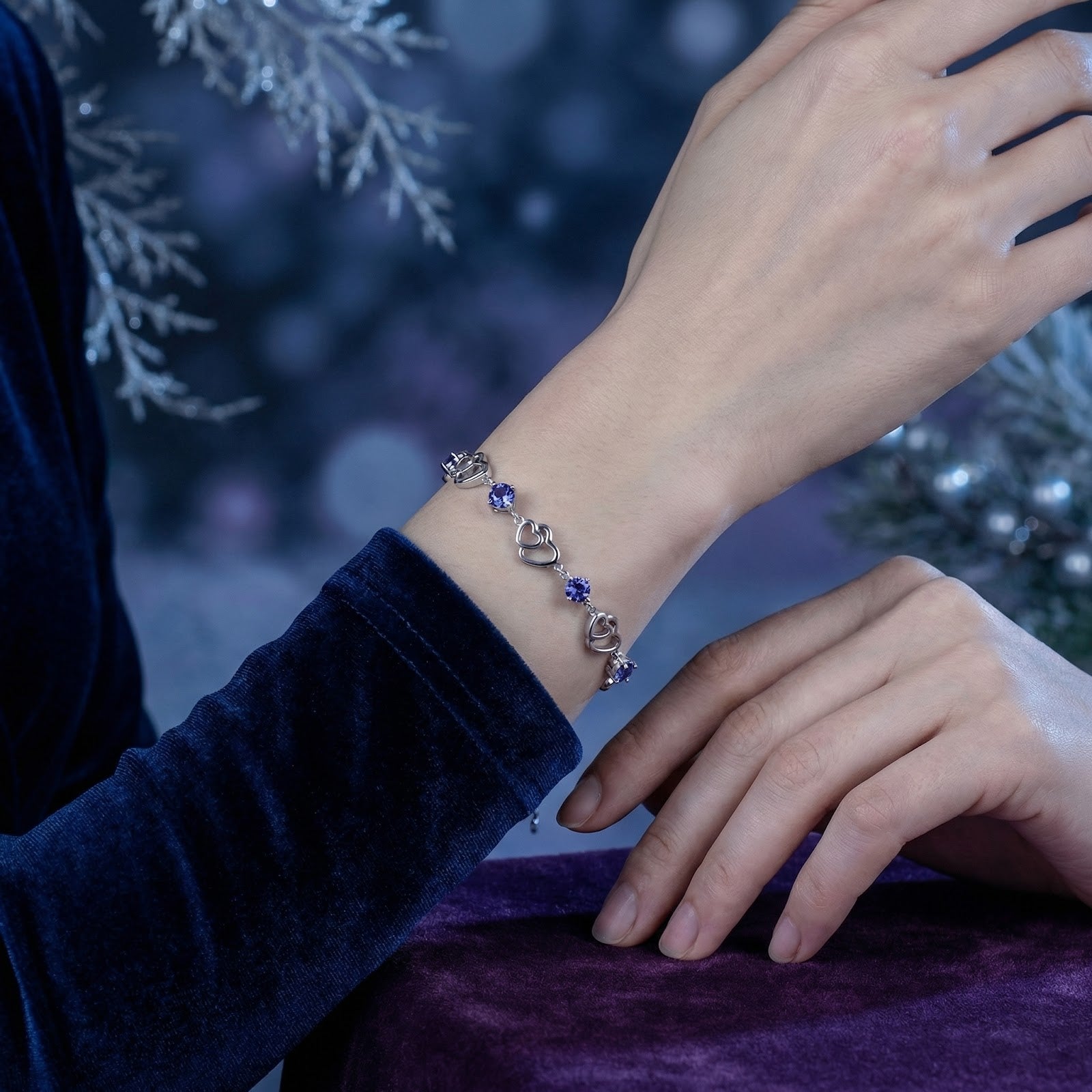 S925 sterling silver heart bracelet with blue simulated tanzanite stones worn on a woman's wrist in a winter setting.