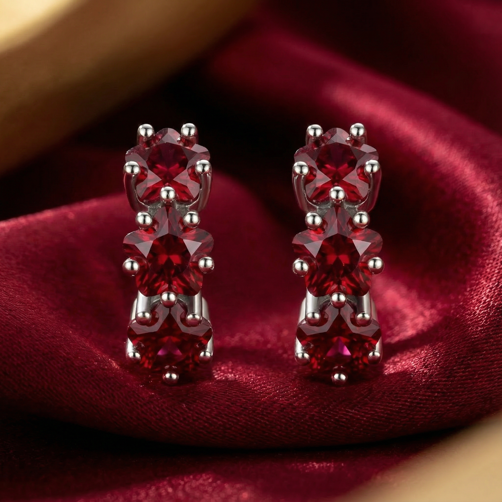 Macro view of star-cut simulated rubies set in sterling silver huggie hoop earrings.